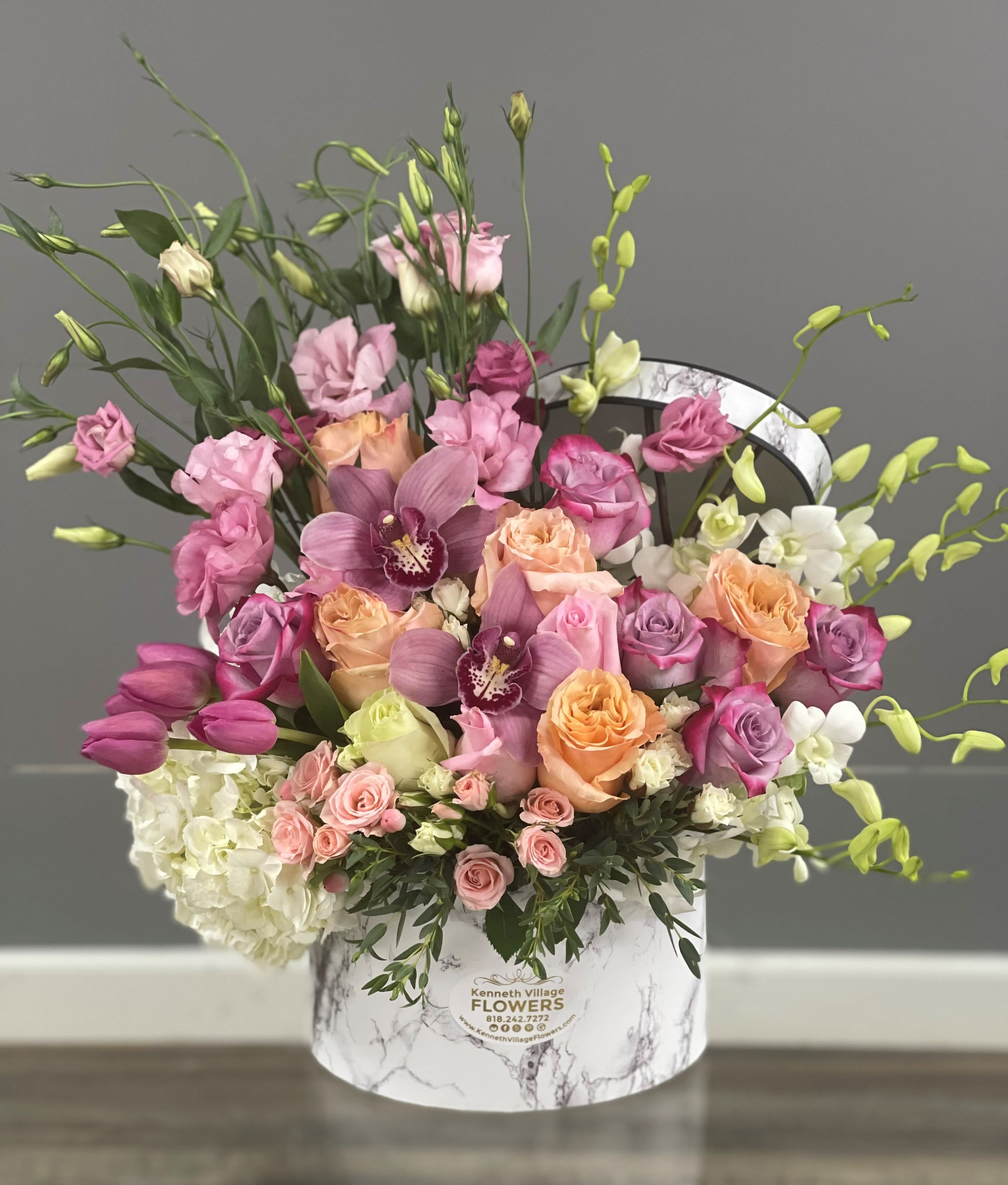 Mixed pink and peach floral arrangement in a marble-print hat box