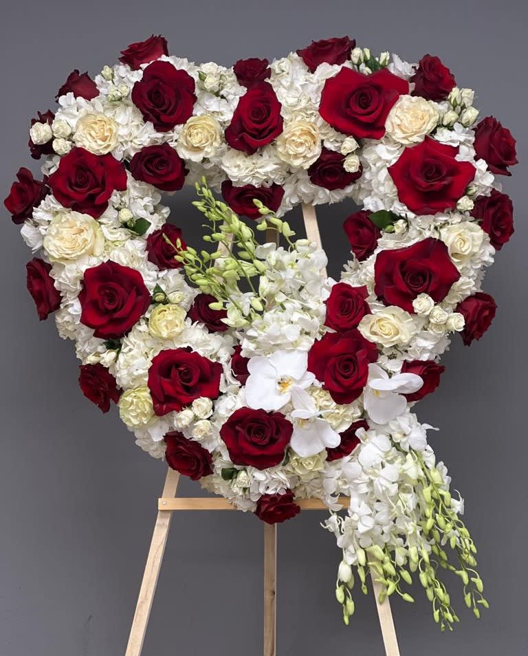 Heart-shaped floral arrangement of red and white roses on an easel