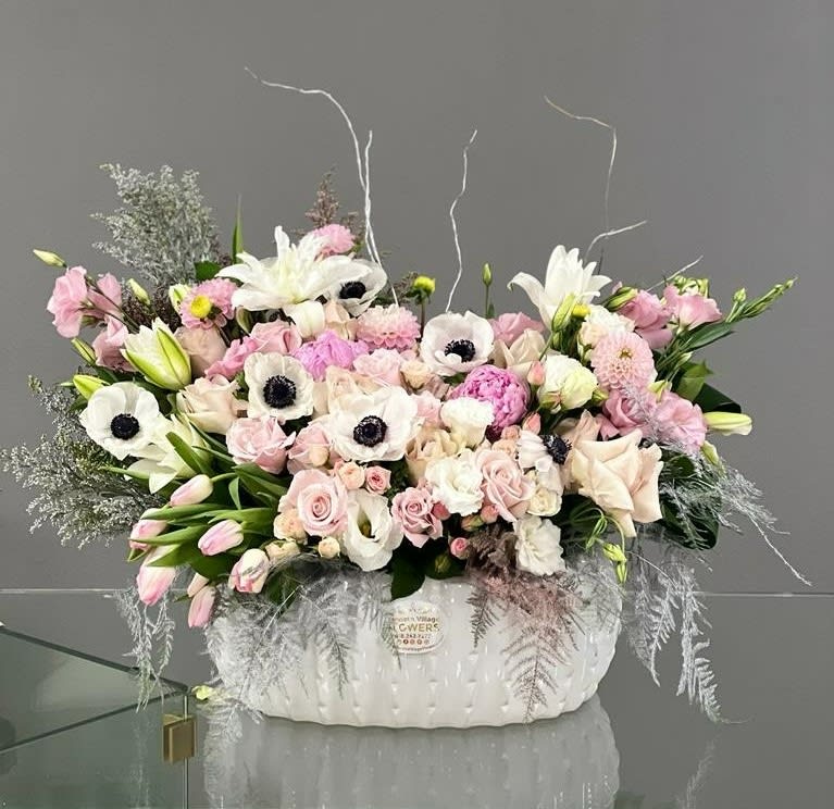 Large pastel flower arrangement in a white ceramic container
