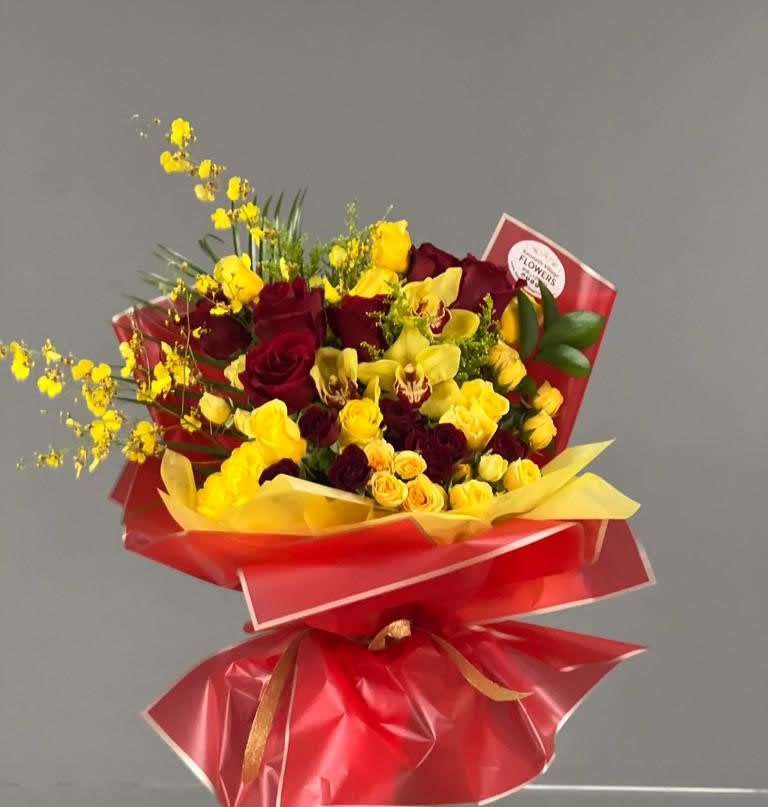 Bouquet of red roses and yellow orchids wrapped in red paper