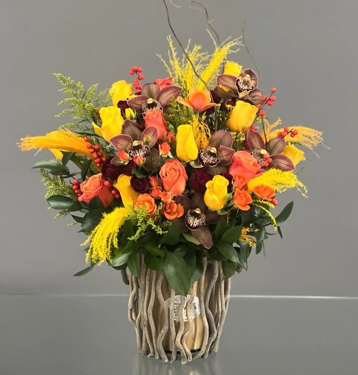 Bouquet of yellow and coral roses with orchids in a decorative vase