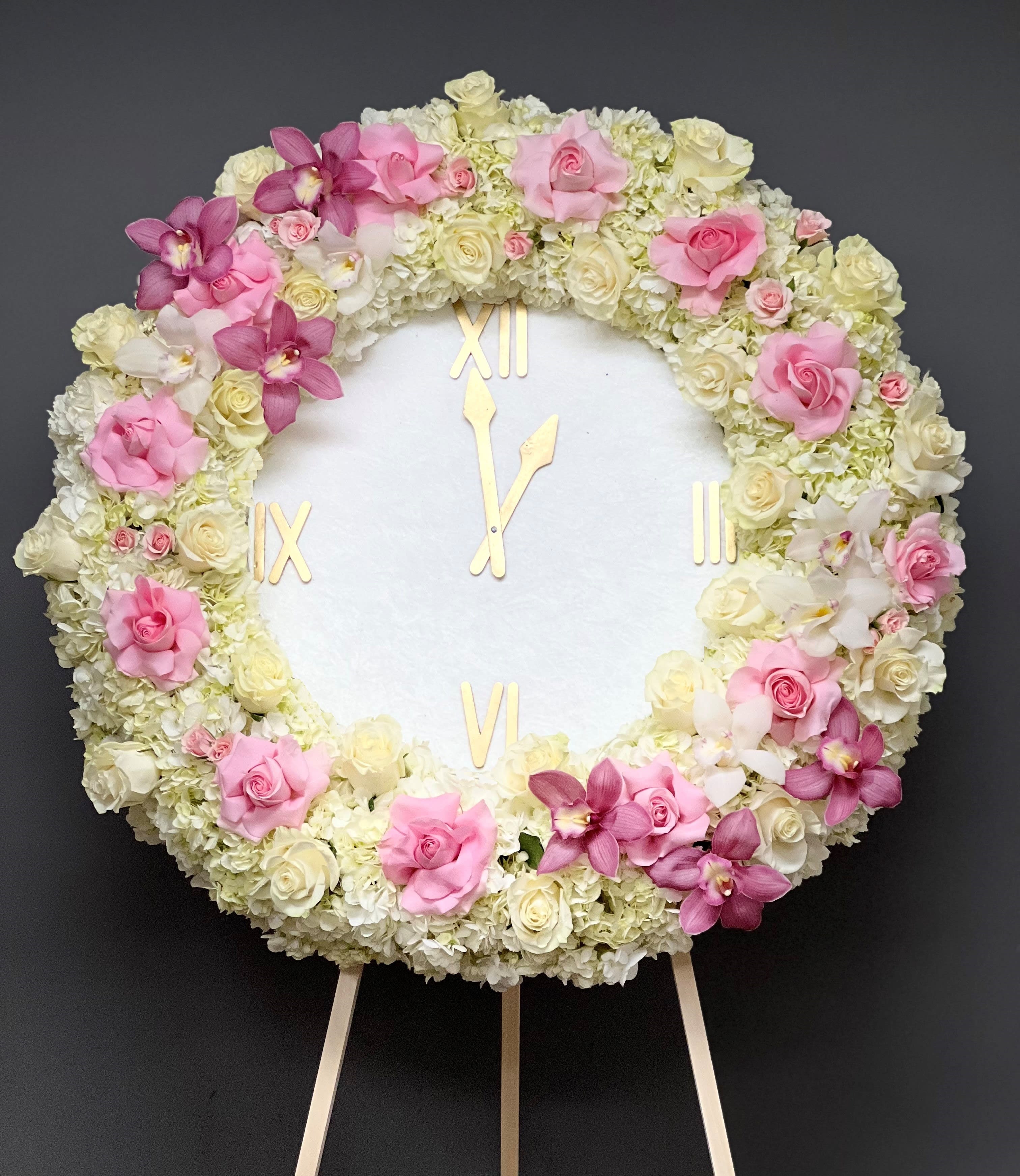 Round floral clock covered in pink and white roses and orchids