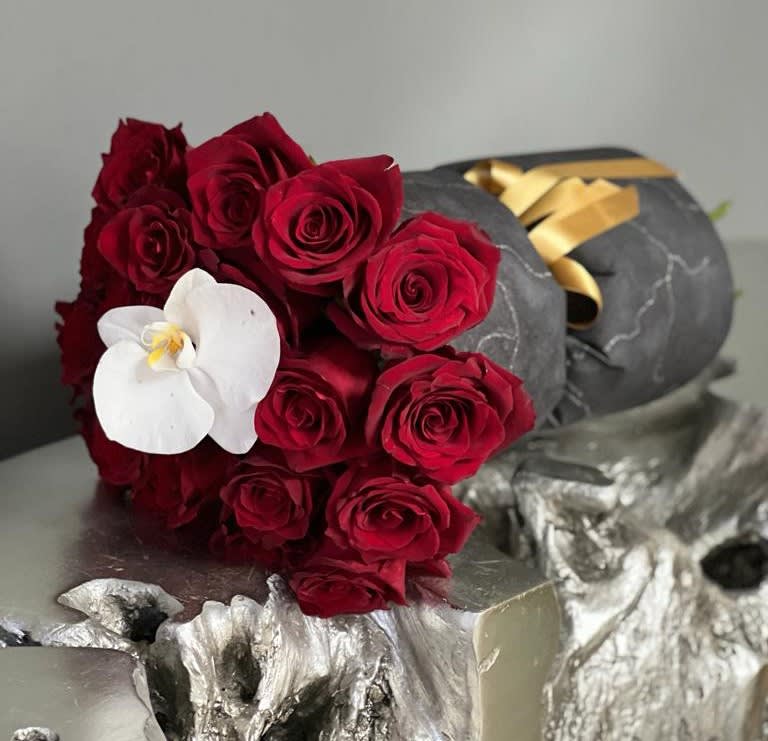 Bouquet of red roses with a white orchid on dark wrapping