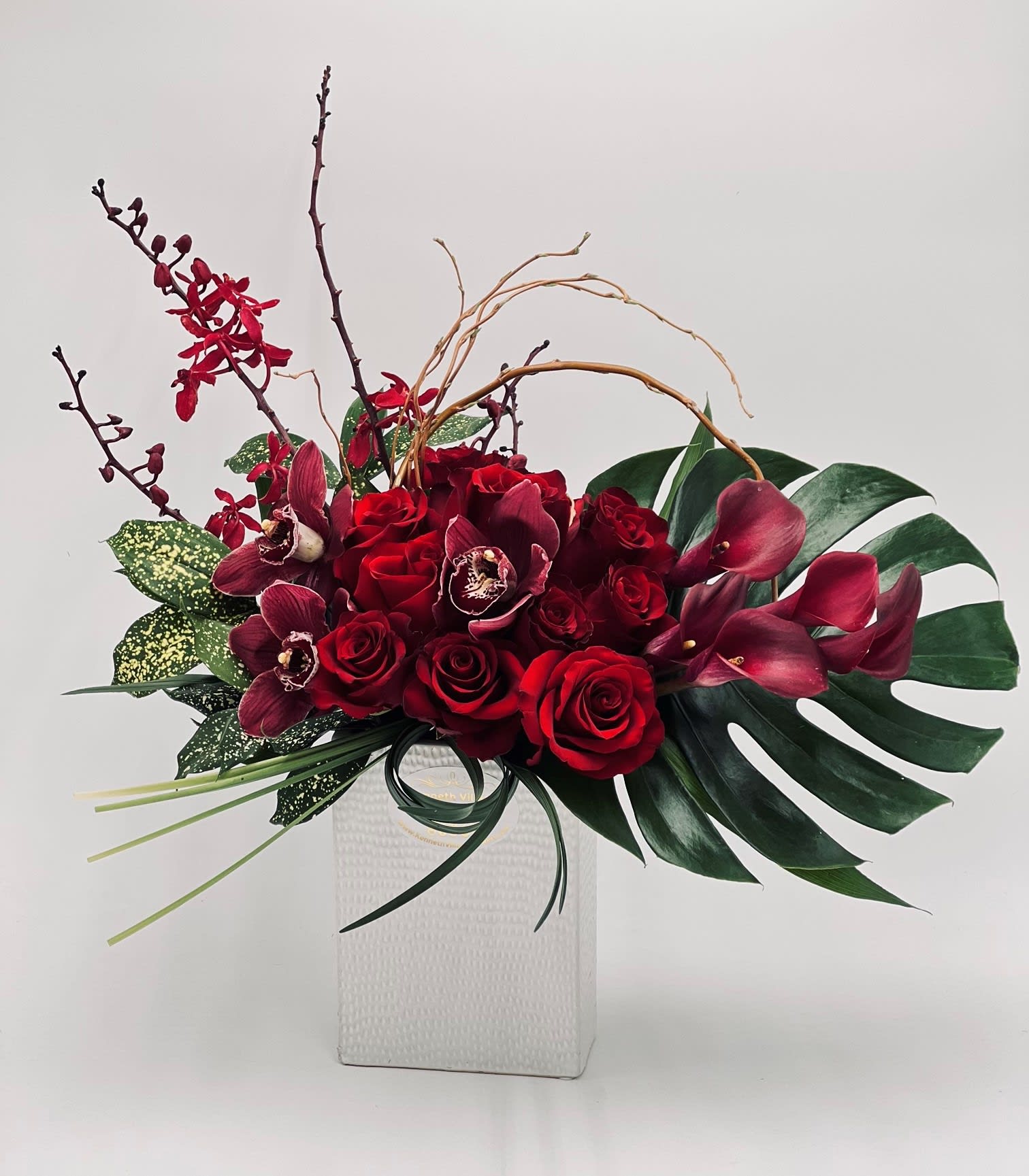 Red roses and burgundy orchids in a white vase