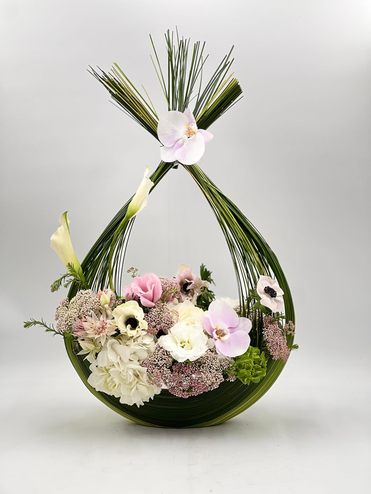 Floral arrangement in a curved green frame with pink and white blooms