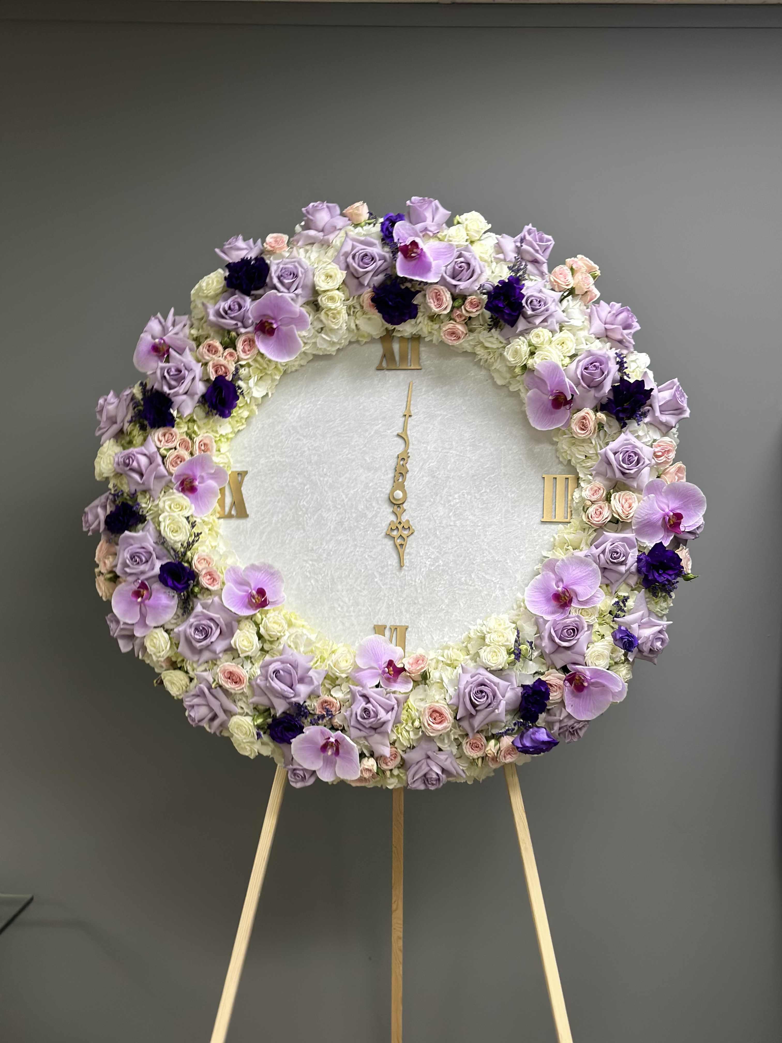 Large round floral wreath on an easel with lavender, white, and pink blooms