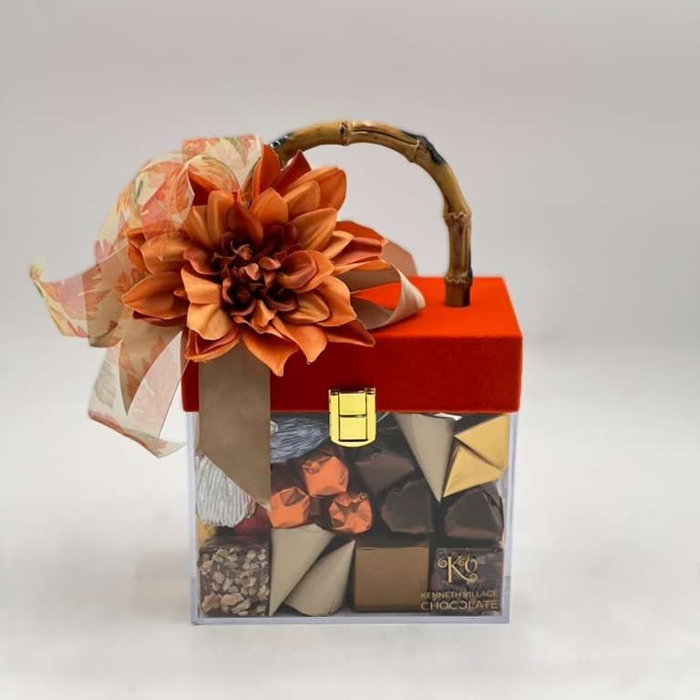 Gift box of assorted chocolates topped with an orange flower and ribbon
