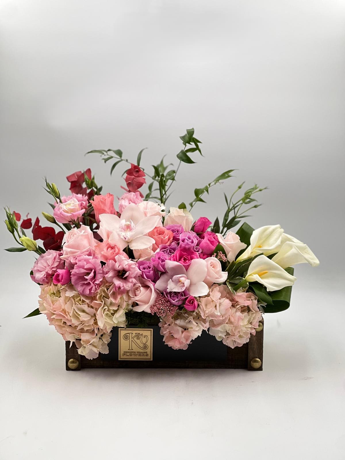 Pink and white floral arrangement in a dark wooden box