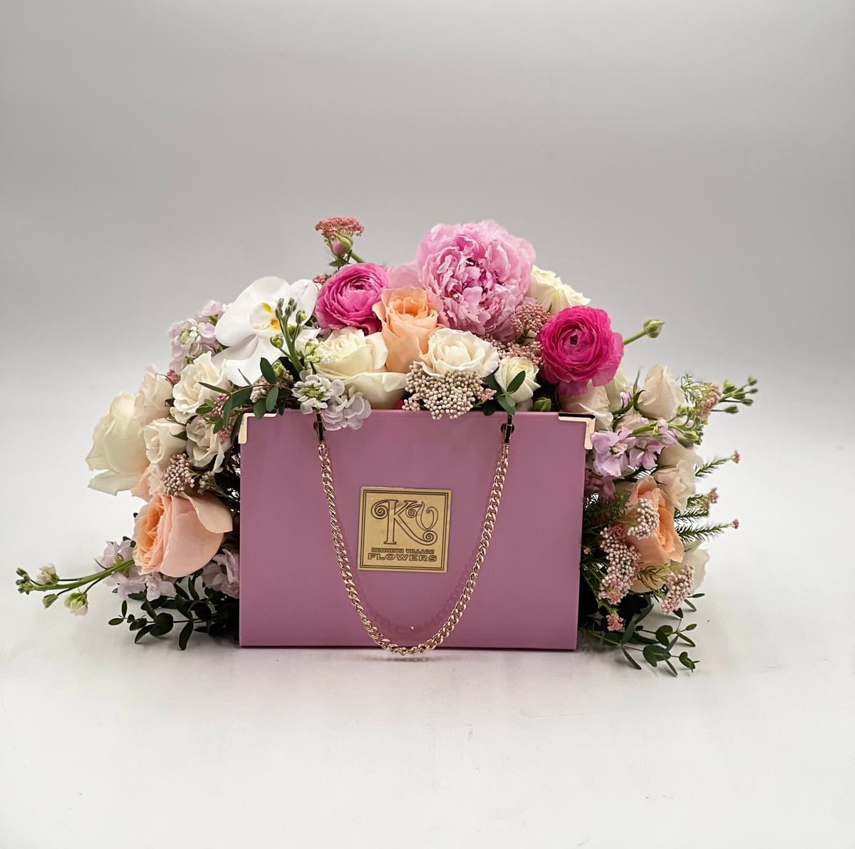 Pink and white flower arrangement in a lavender gift box with a chain handle