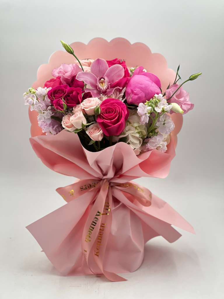 Sweet Pink Romance - A soft and elegant hand-tied bouquet designed in romantic shades of pink, featuring premium seasonal accent blooms. Wrapped in luxurious blush paper with a satin ribbon, this arrangement is perfect for birthdays, anniversaries, congratulations, or simply sending love.