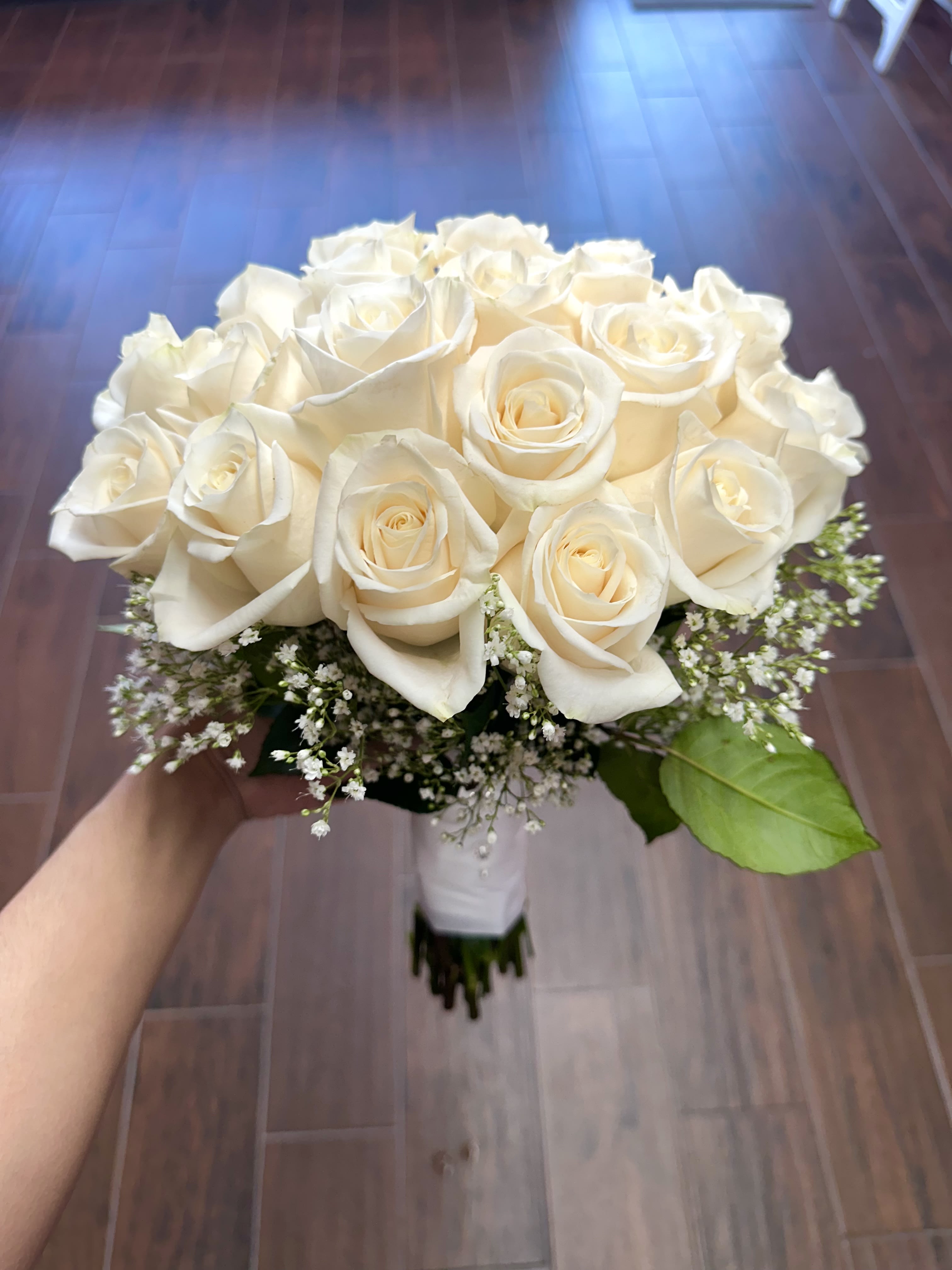 Bouquet of white roses with baby's breath and a single green leaf