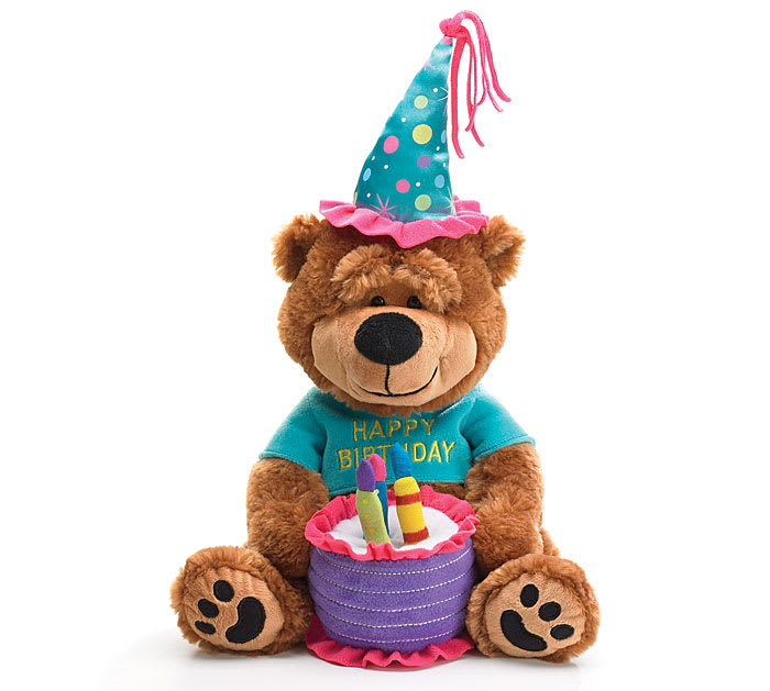 Plush teddy bear wearing a birthday hat and shirt, holding a toy cake
