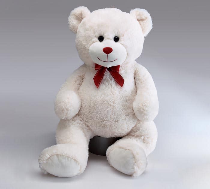 White teddy bear with a red bow sitting on a gray background
