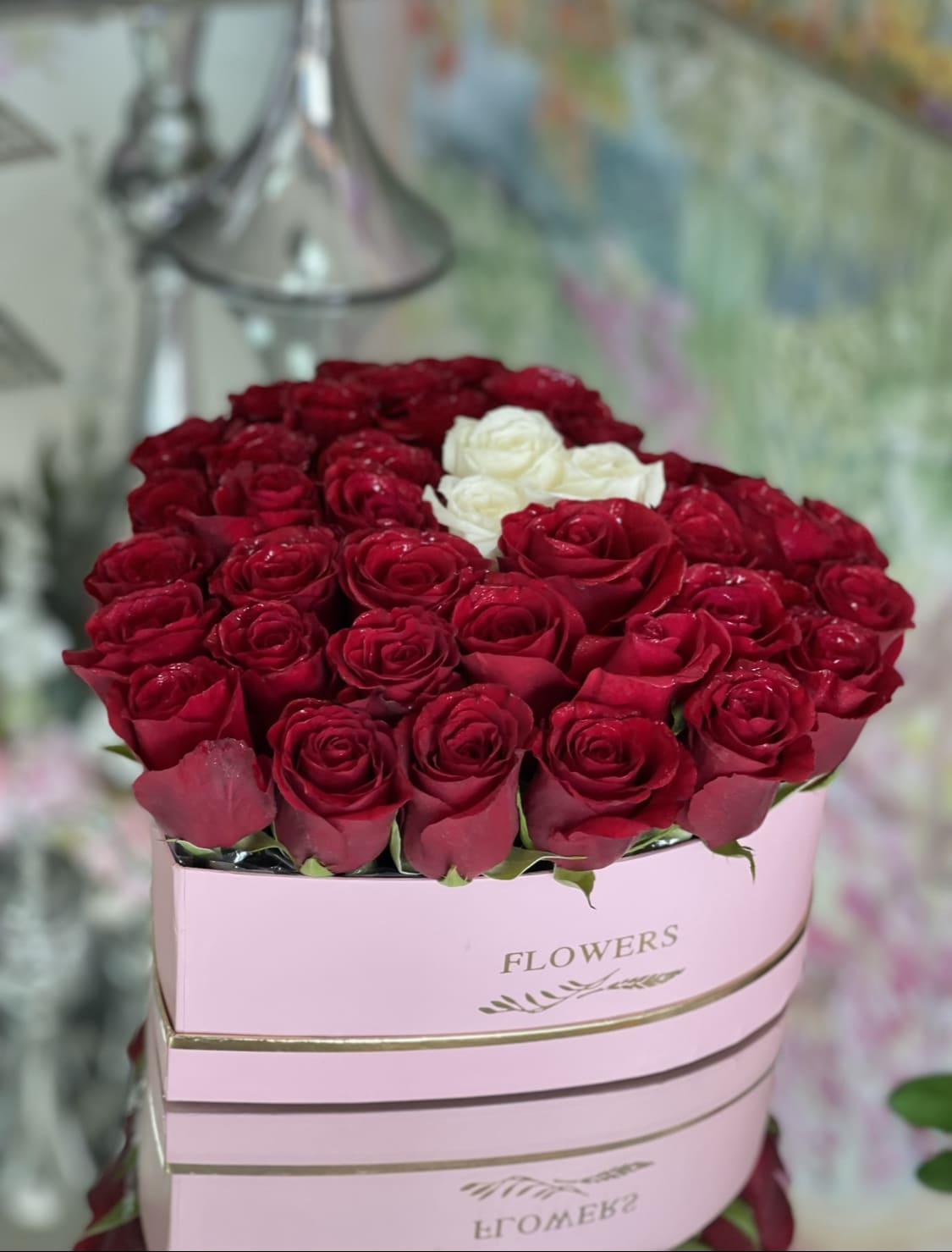 Red and white roses arranged in a pink hat box
