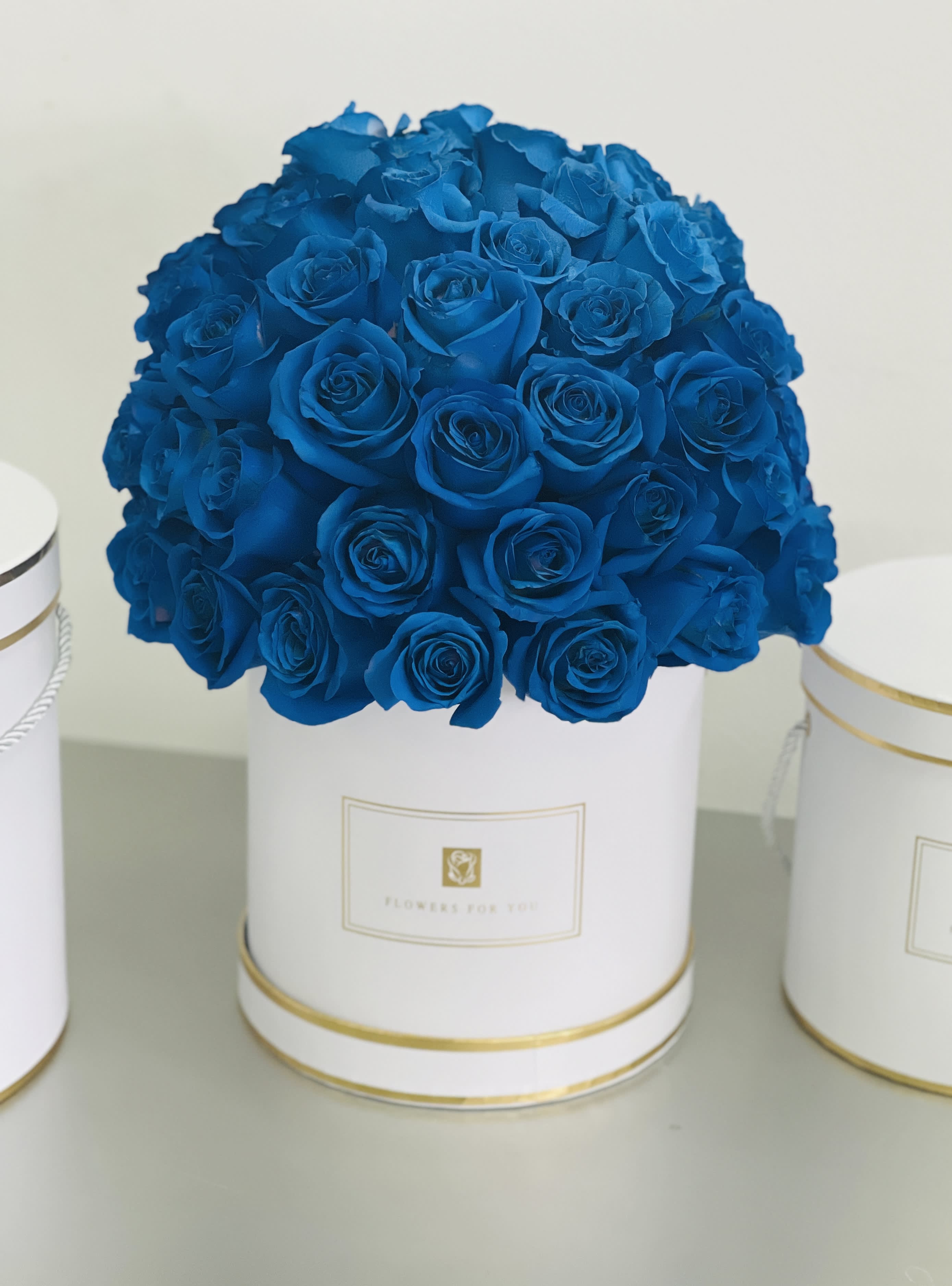 Blue Roses in a Cylinder White Box - Made with tinted Ecuadorian roses  Rose count 50-60 Approx. this flower box is the perfect for any occasion *box Material: Cardboard 7"x7"  