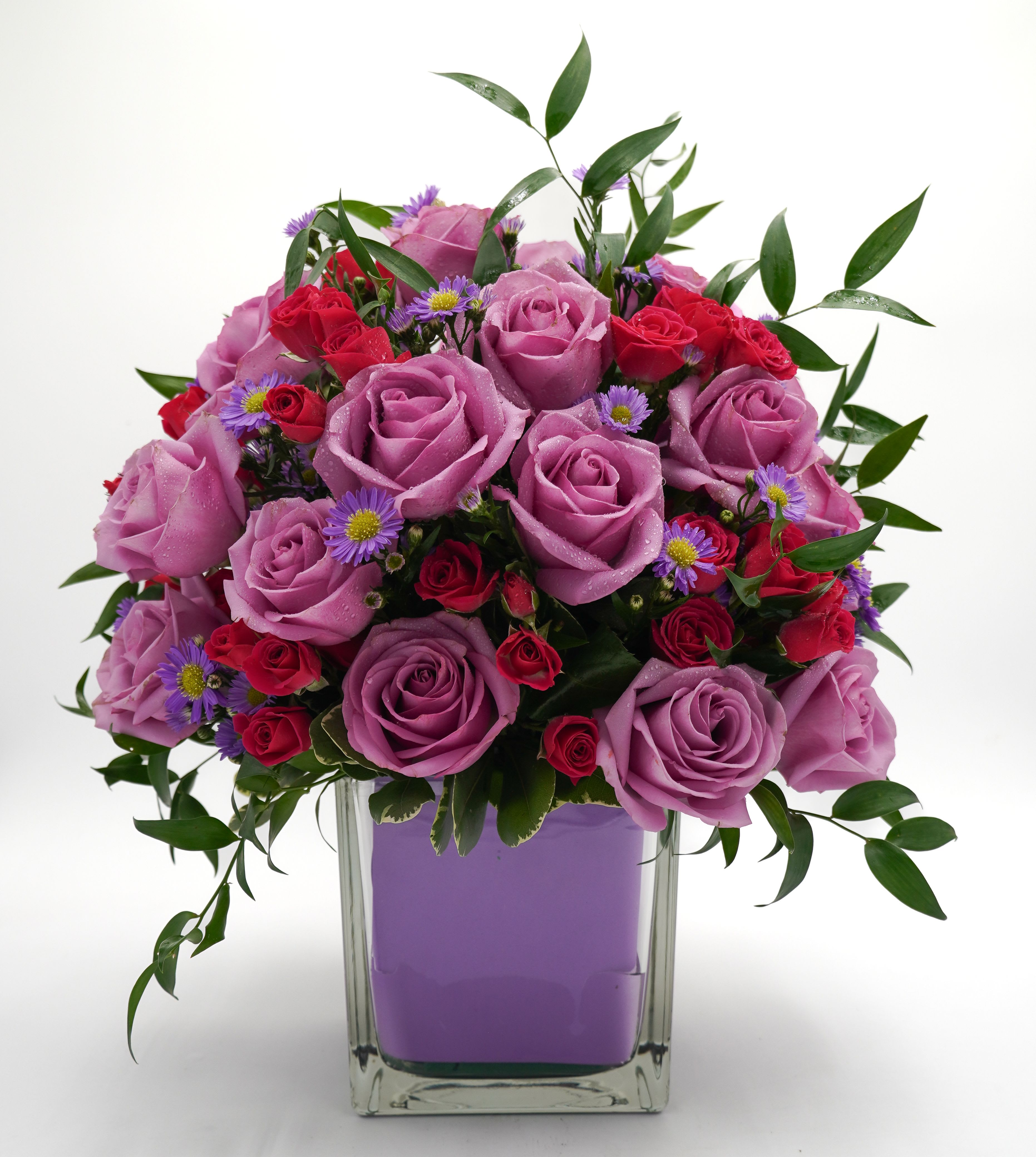 Lavender and red rose bouquet in a clear square vase