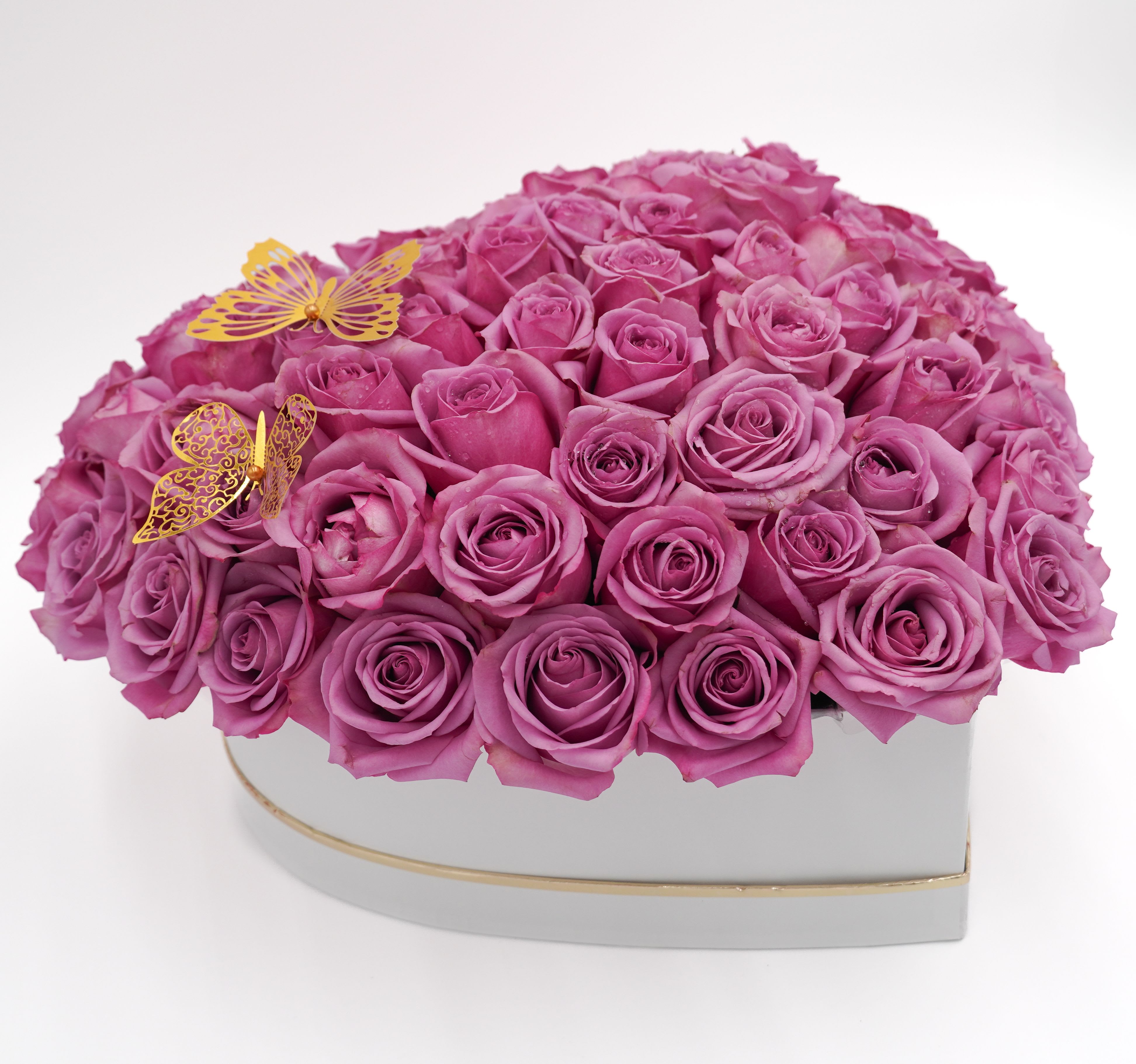 Heart-shaped box filled with pink roses and two gold butterfly decorations