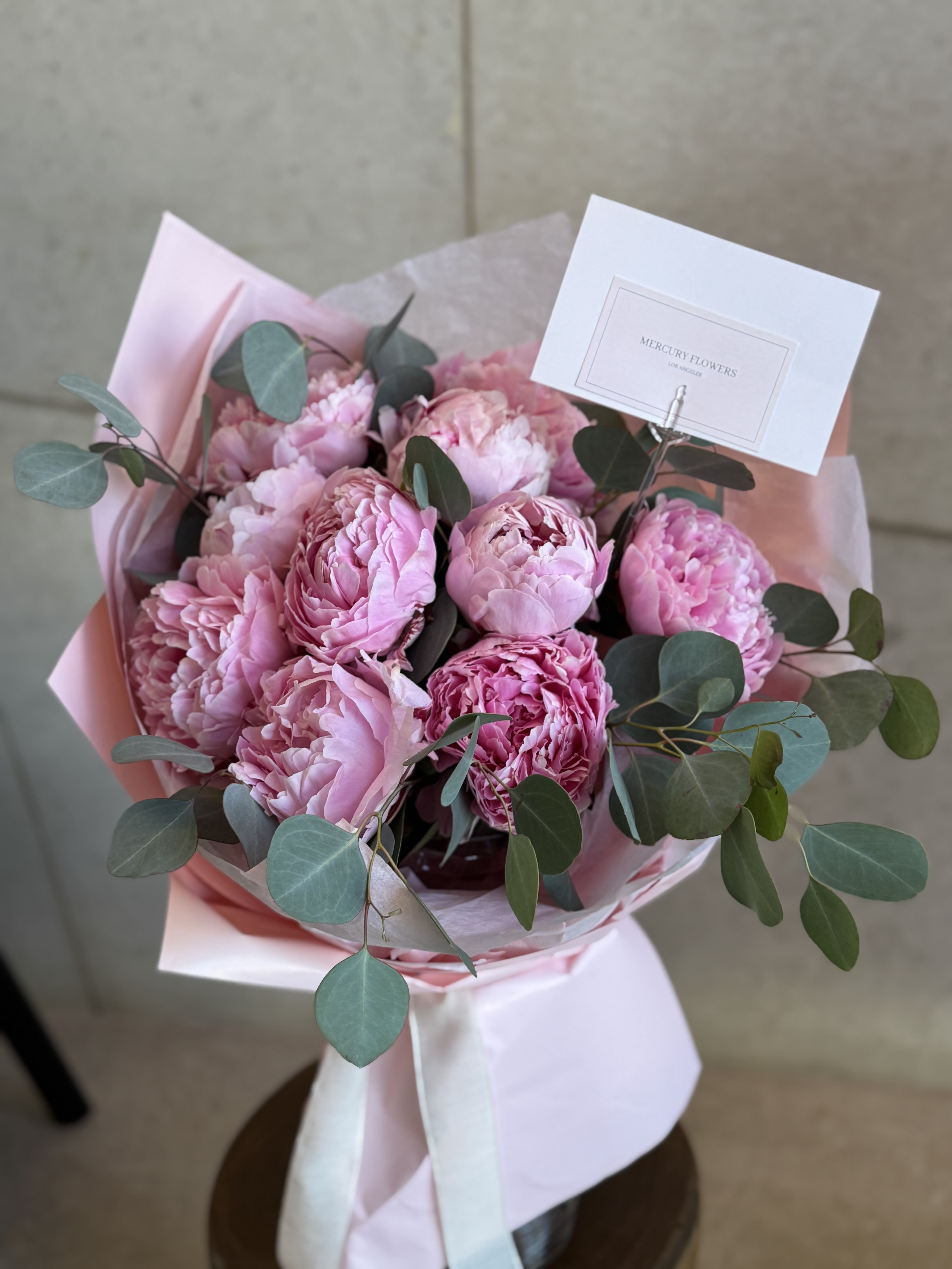 Pink peony bouquet with eucalyptus in pastel wrapping
