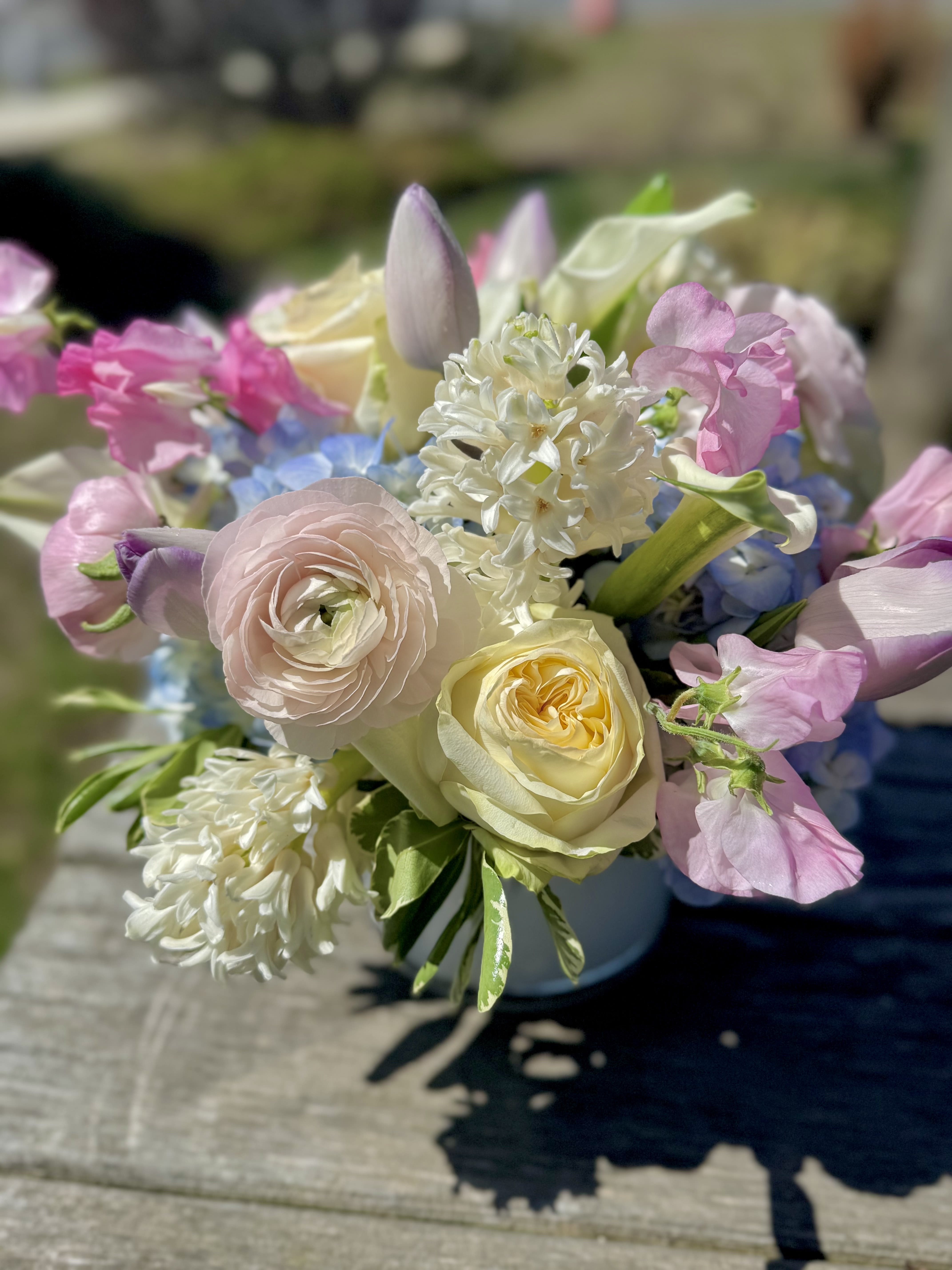 Pastel bouquet with roses, ranunculus, and mixed blooms in a vase