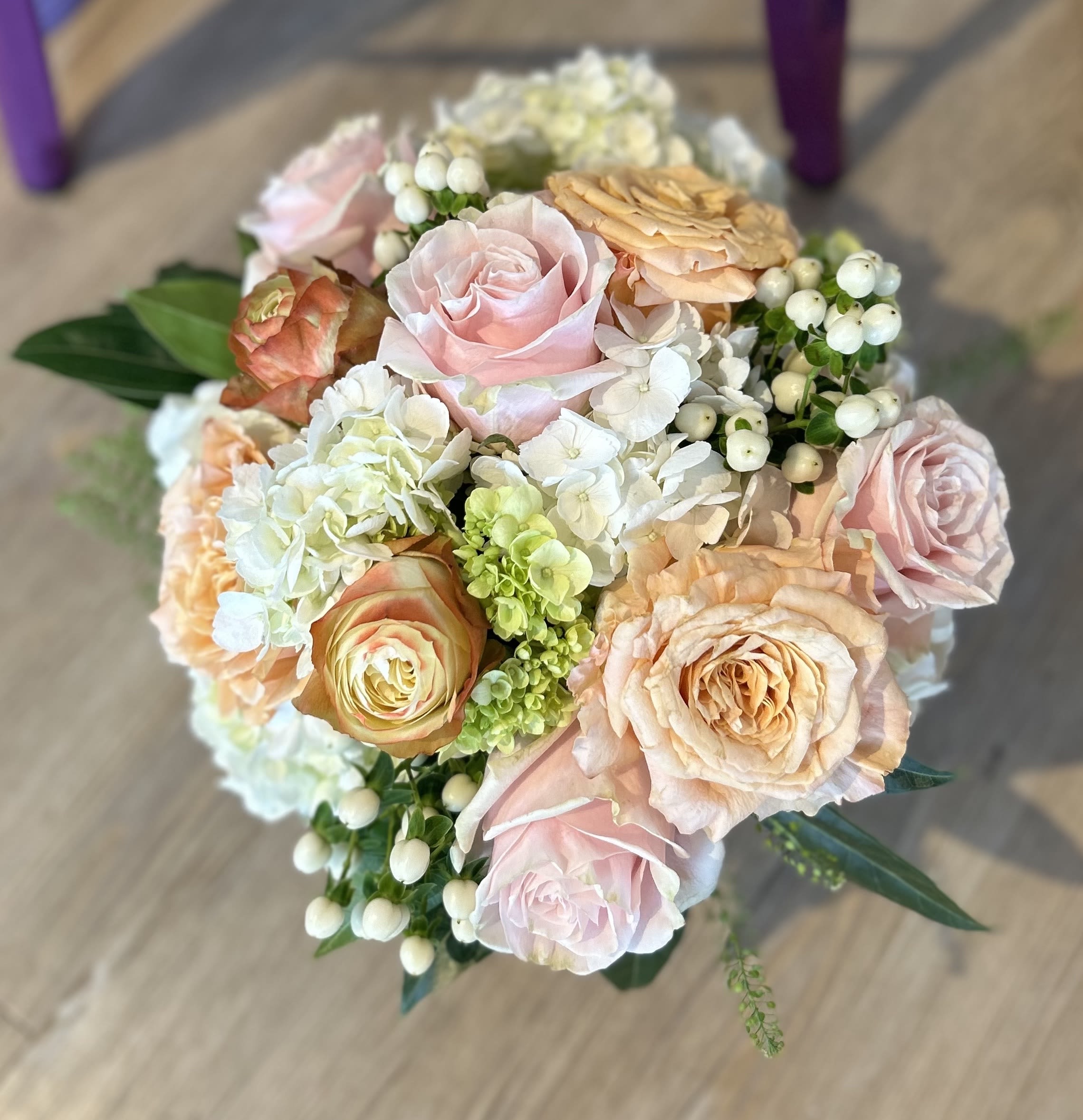 Bouquet of blush and peach roses with white hydrangea and berry accents