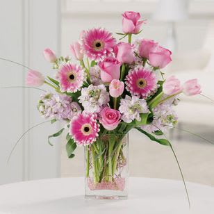 Pink gerberas and roses arranged in a clear glass vase