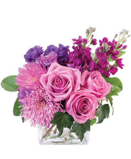Pink and purple flower arrangement in a clear square vase