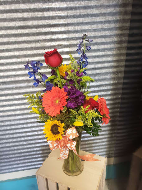 Colorful mixed bouquet in a glass vase with a ribbon