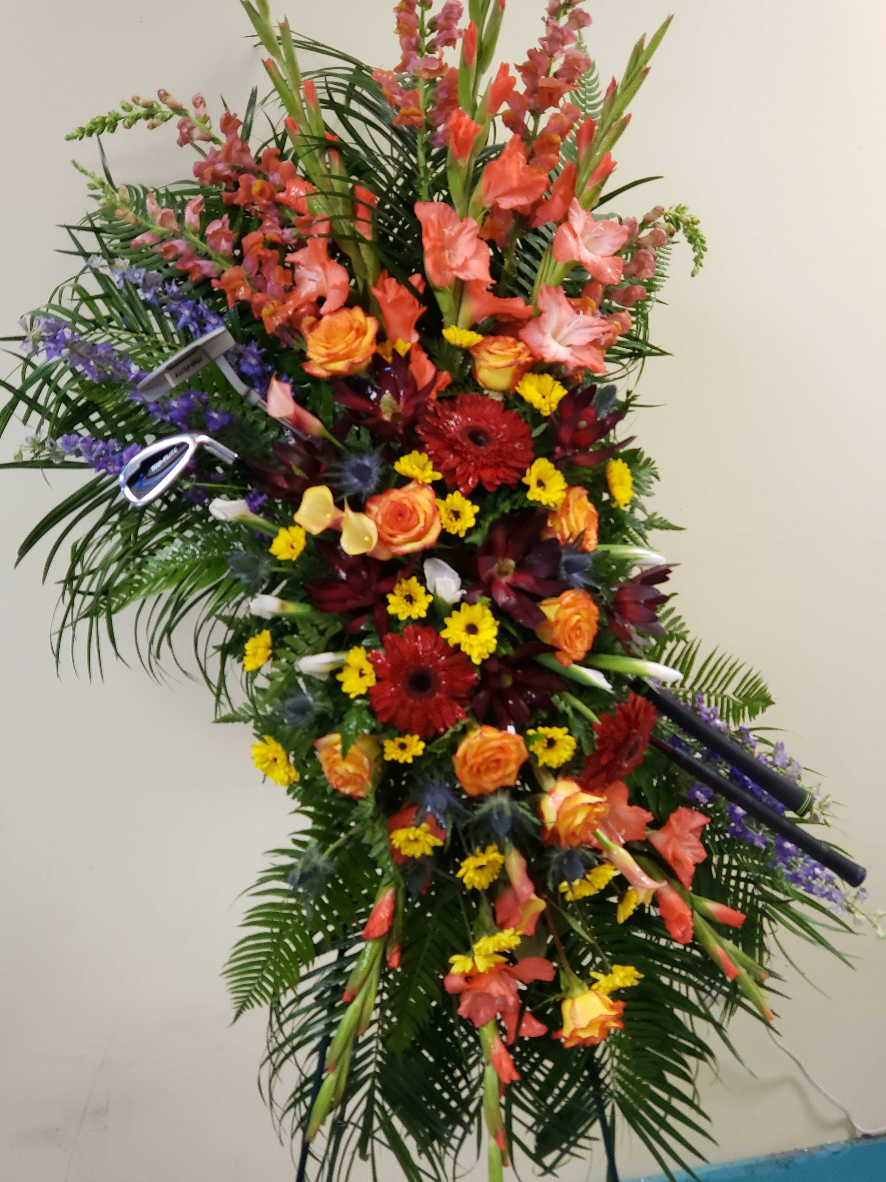 Tall standing floral spray with orange, red, yellow, and purple flowers