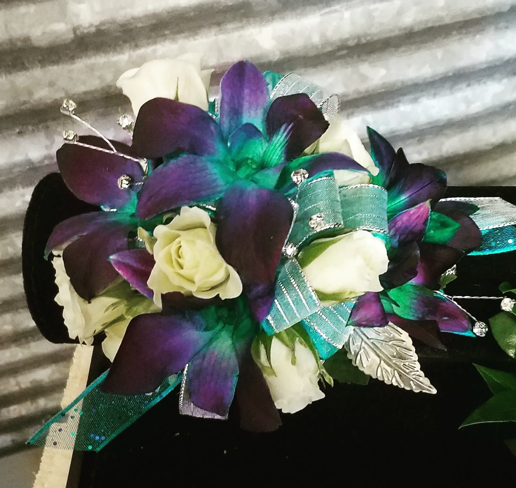 Bouquet of white roses with purple and teal orchid-like flowers and ribbon