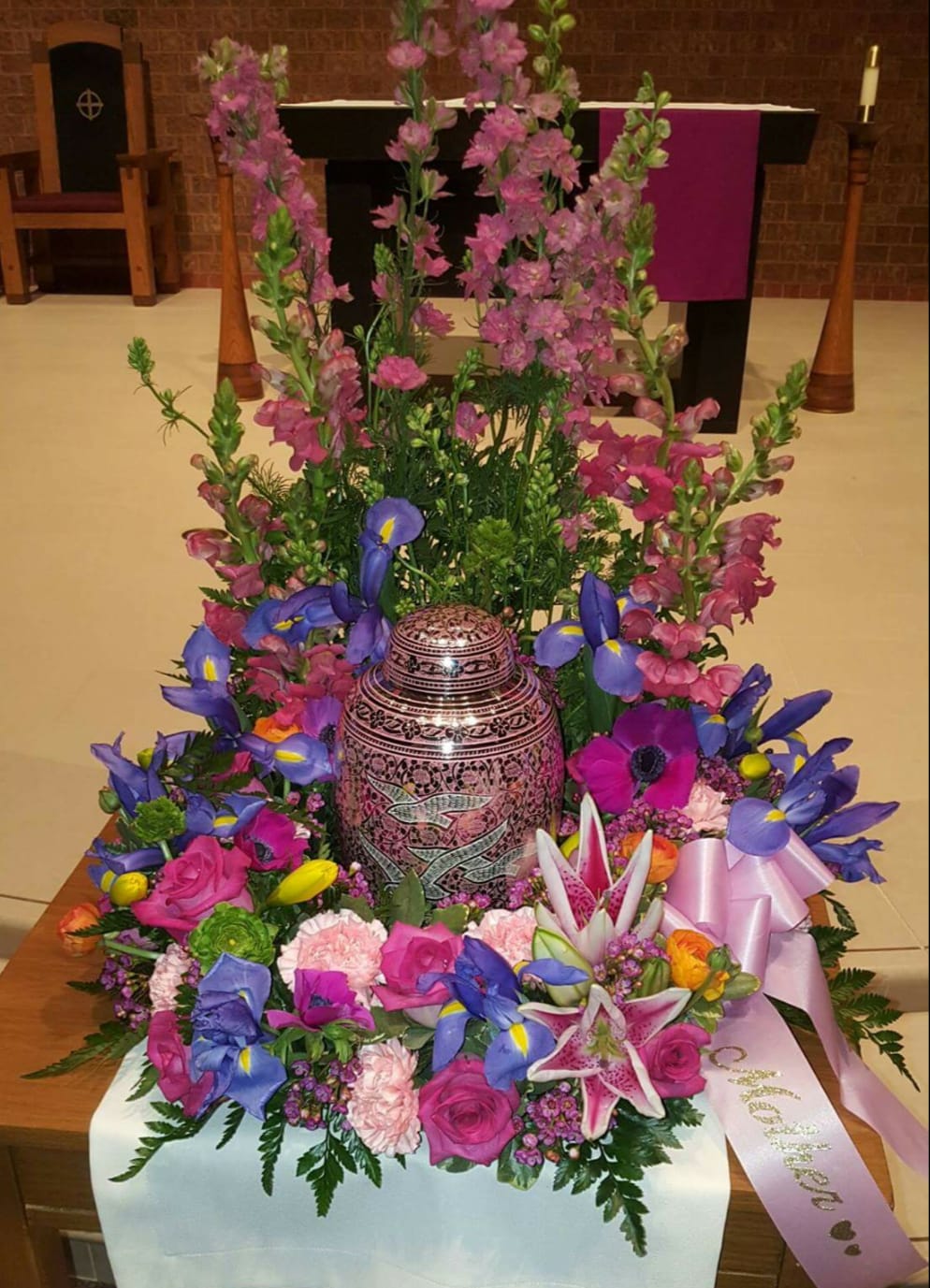 Colorful floral arrangement around a decorative urn in a church setting