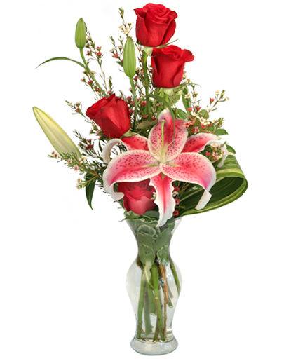 Red roses and a pink lily in a clear glass vase