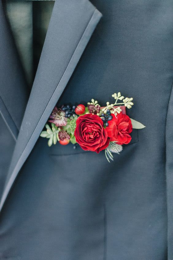 Red floral boutonniere pinned to a dark suit jacket