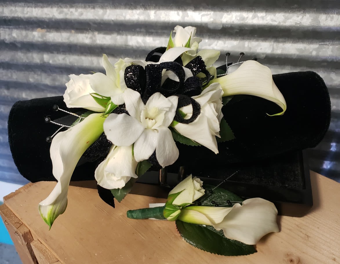 White calla lilies and orchids with black ribbon on a black cushion