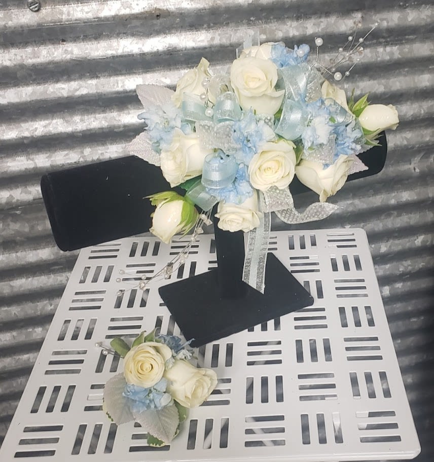 White rose bouquet with pale blue accents and ribbon on a black stand