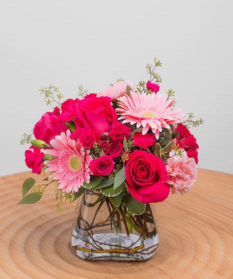 Pink roses and gerbera daisies arranged in a clear glass vase