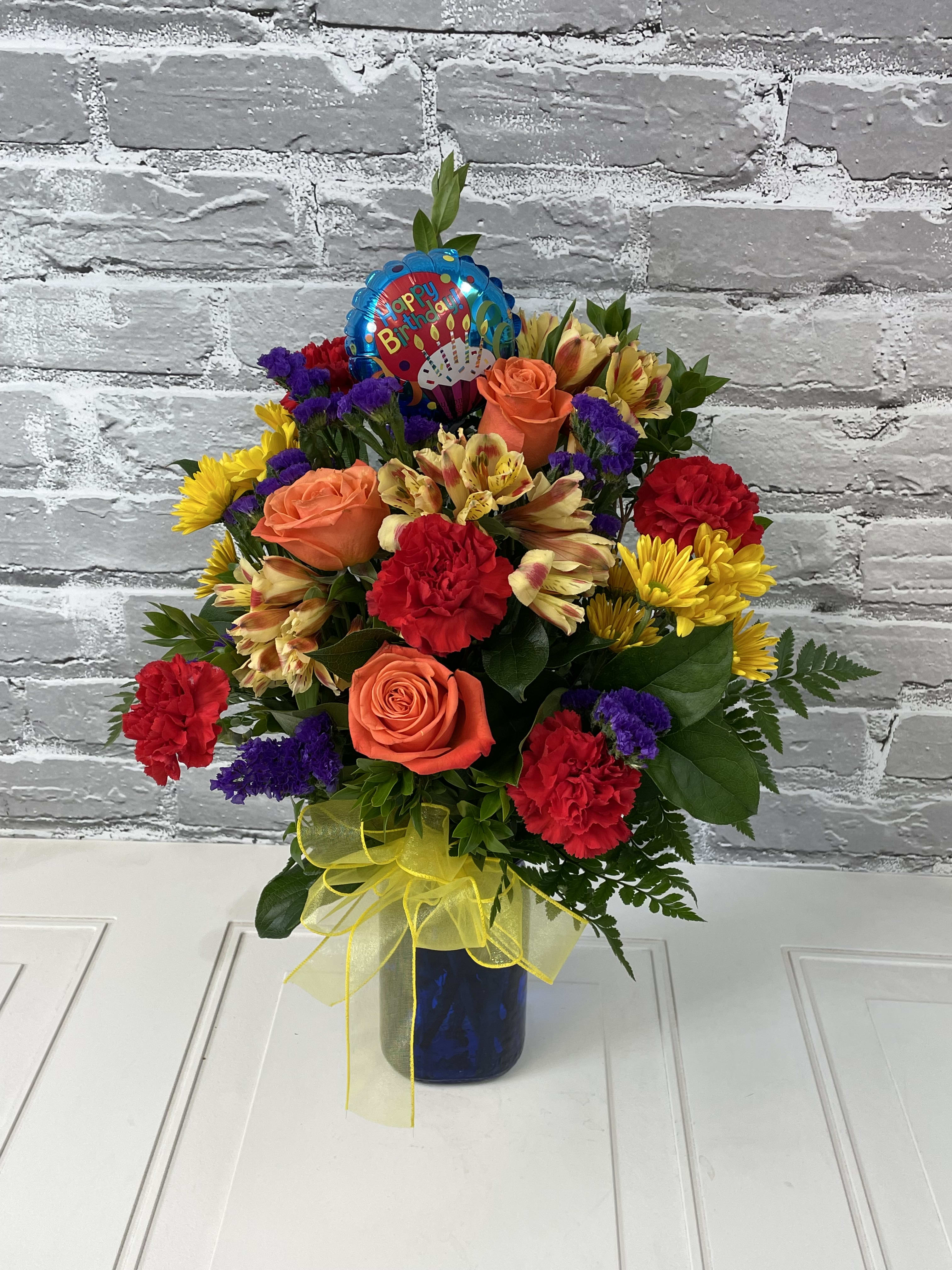 Colorful birthday bouquet in a blue vase with a balloon topper