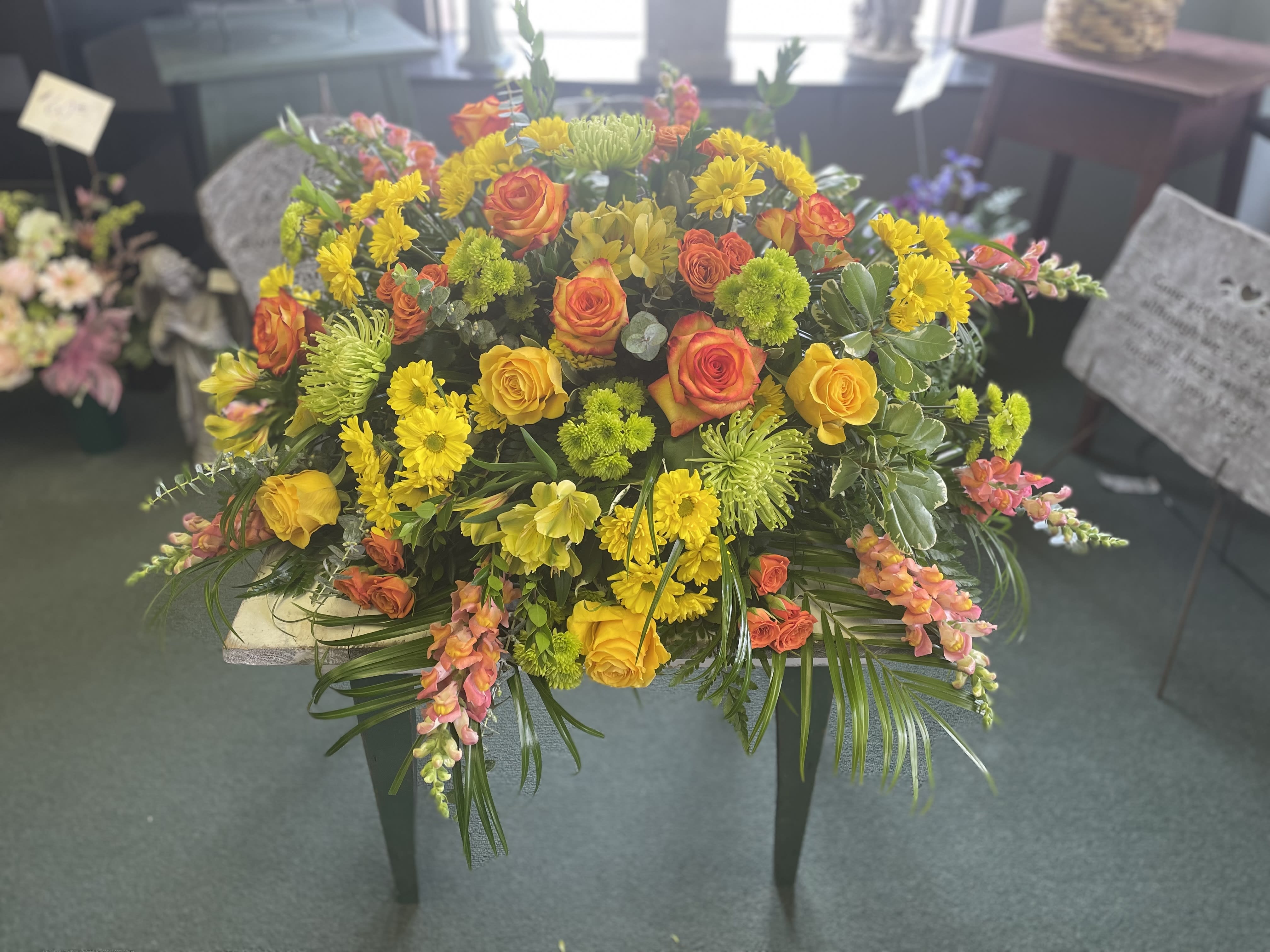Large bouquet of yellow and orange flowers with greenery on a table