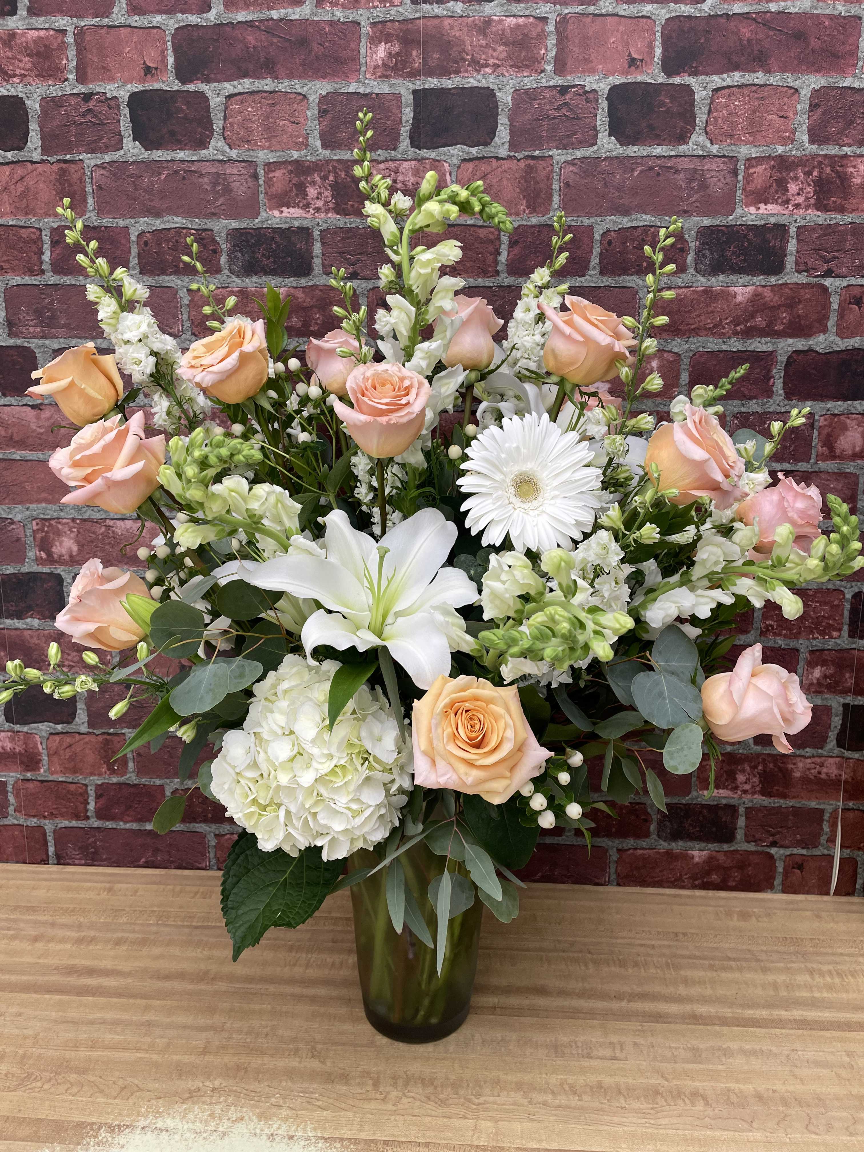 Peach roses and white lilies in a glass vase