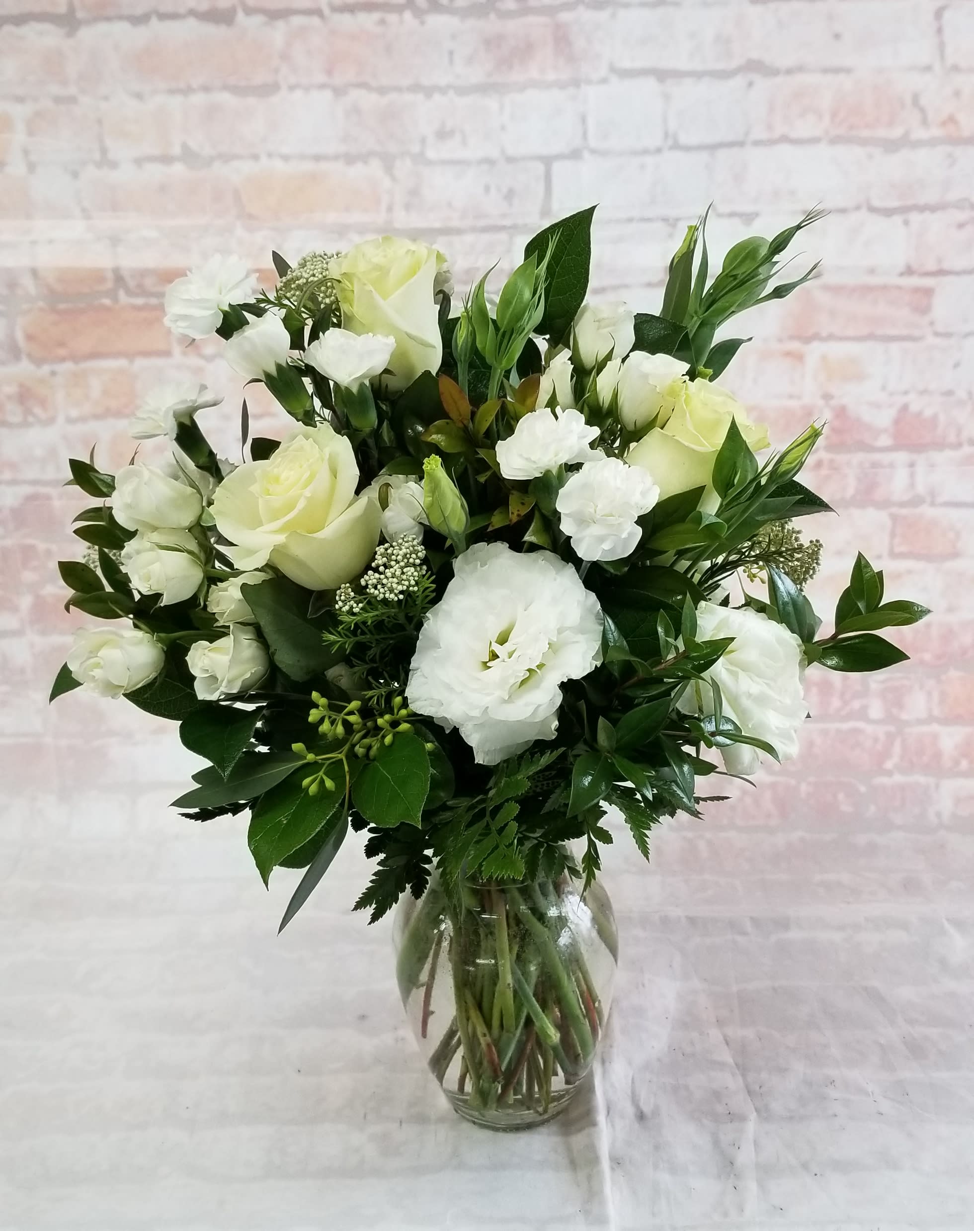 Pure &amp; Beautiful - Select this pure white combination of flowers in a clear glass vase. Flowers include roses, spray roses, lisianthus and mini carnations.