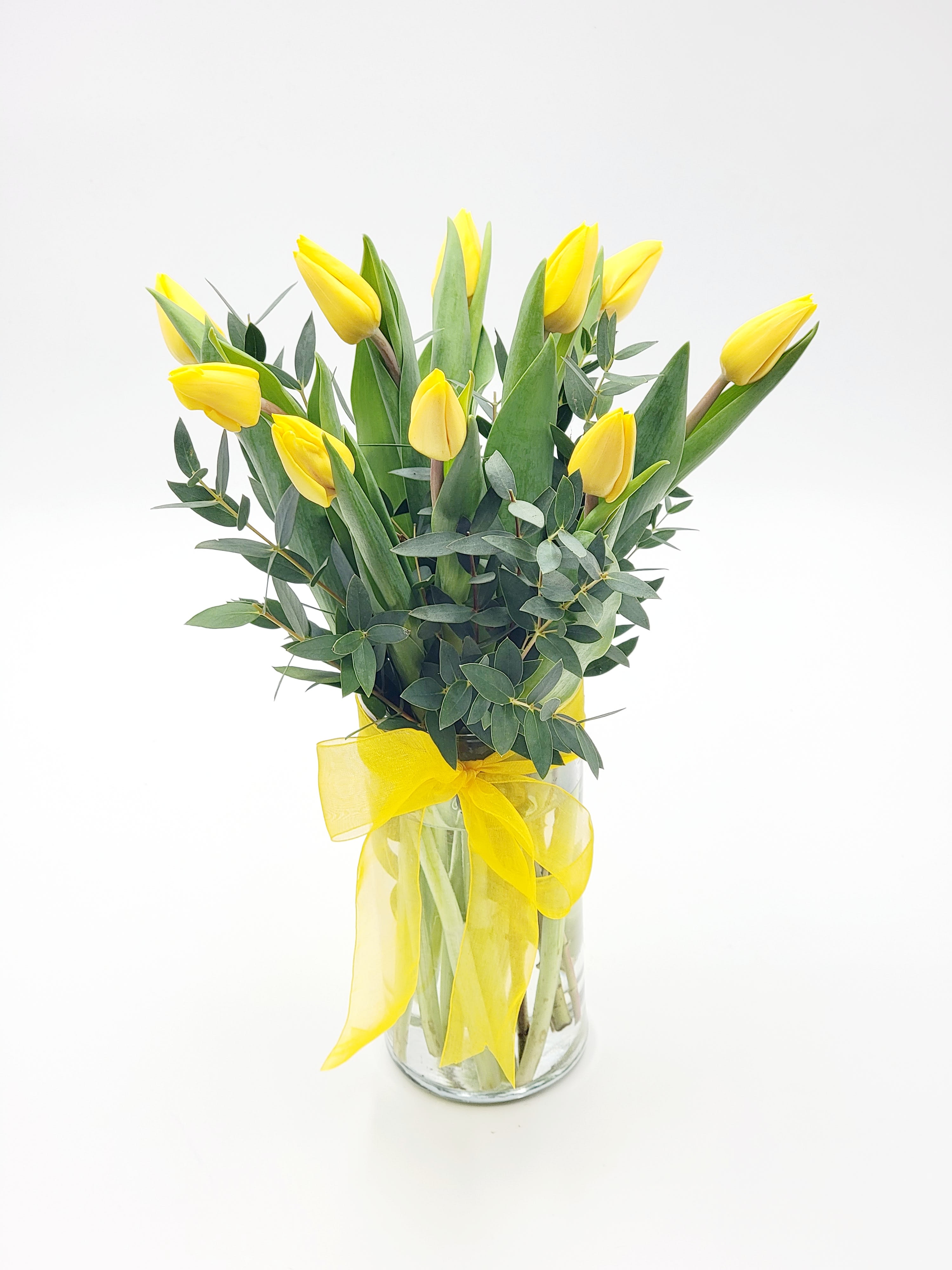 Sunny Yellow Tulips - Sunny yellow tulips are a sure sign of spring. Even if the weather is not cooperating you can be sure the person who receives this bright bouquet will feel the warmth of your message. Dazzling yellow tulips are delivered in an exclusive glass vase that's all wrapped up with?what else?a bright yellow ribbon. So go ahead and send sunshine. Even (or especially) if it's a cloudy day!Approximately 12 1/2" W x 14 3/4" H Orientation: All-Around As Shown : T140-1ADeluxe : T140-1BPremium : T140-1C