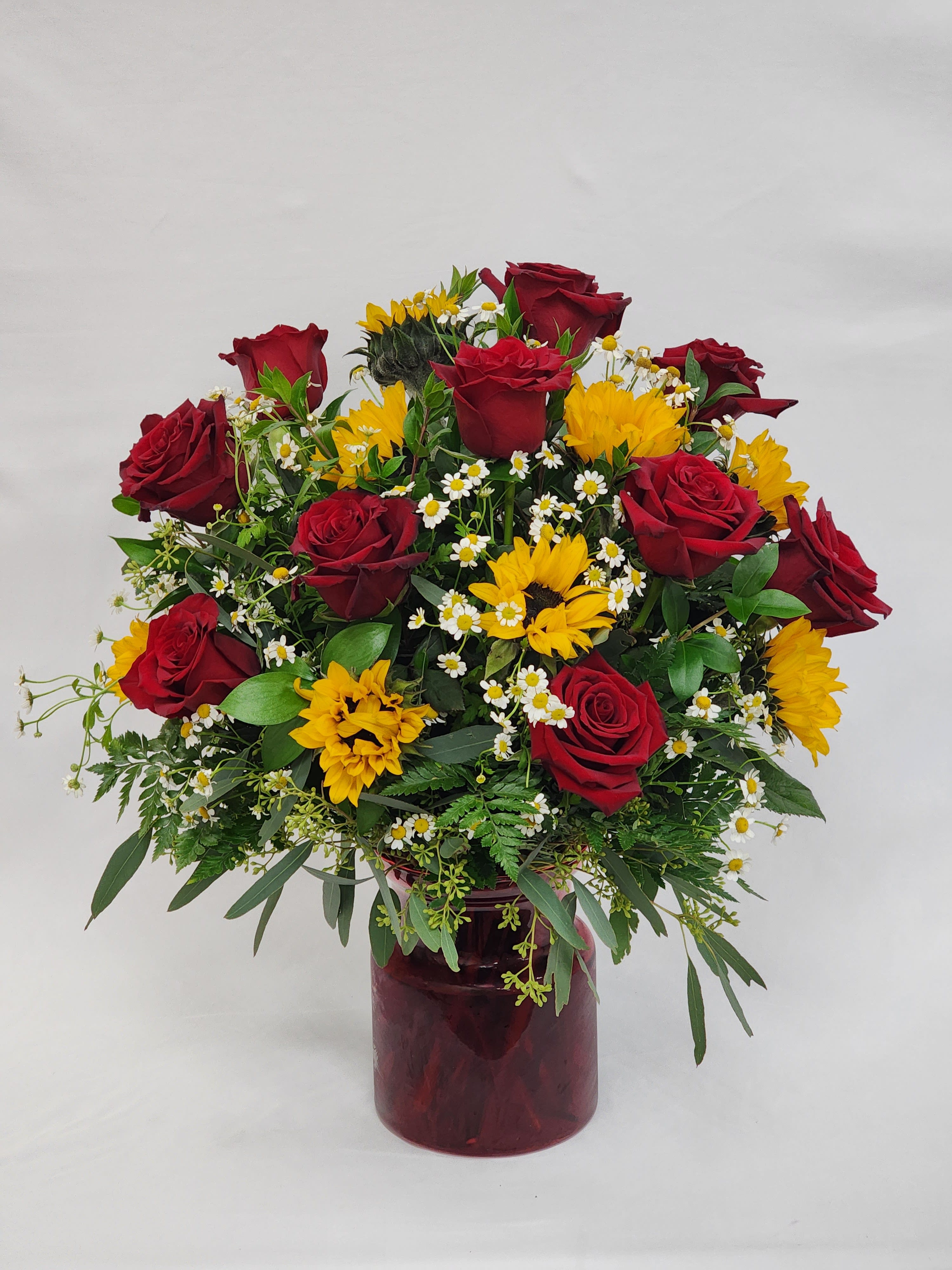  Timeless - Select this beautiful arrangement of a dozen red roses, sunflowers, and chamomile.  Roughly 21" x 16"