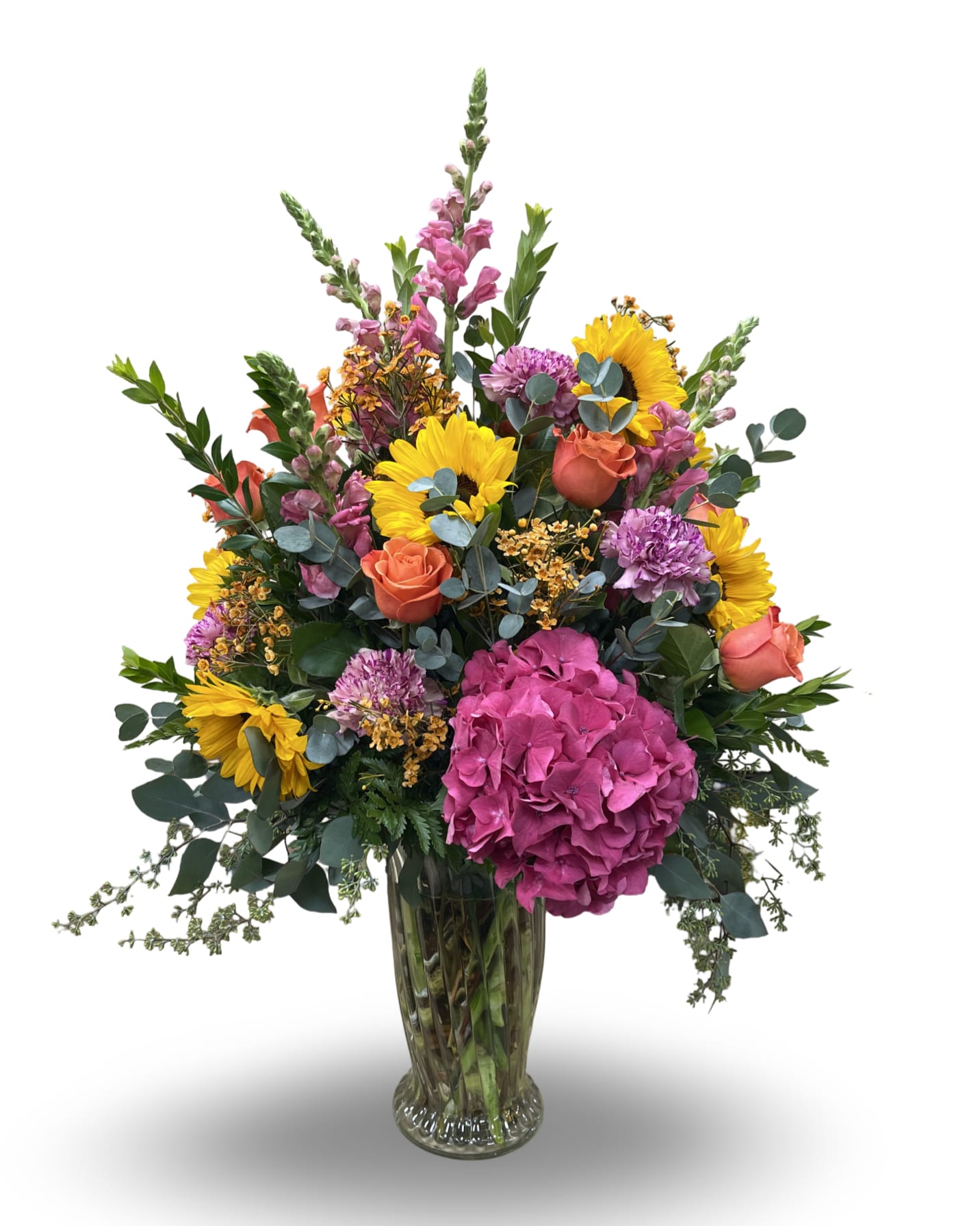 Autumn Aura - Autumn Aura is a vibrant arrangement standing about 36 inches tall, 18 inches wide, and 24 inches long. Designed in a clear glass vase, it features a rich mix of seasonal blooms including golden sunflowers, roses, pink hydrangea, snapdragons, carnations, and lush greenery. With flowers beautifully arranged to be enjoyed from every angle, this full and radiant design brings the warmth and joy of autumn to any occasion.