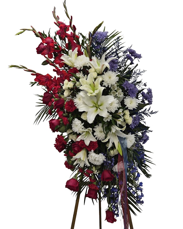 Freedom's Tribute - Freedoms Tribute is a heartfelt standing spray designed in classic red, white and blue tones to honor a life remembered with pride and love. Featuring elegant lilies, roses and other complimentary flowers, this meaningful display offers a beautiful way to express respect, remembrance, and gratitude. A touching tribute for services celebrating a life of strength, service, and lasting legacy. 