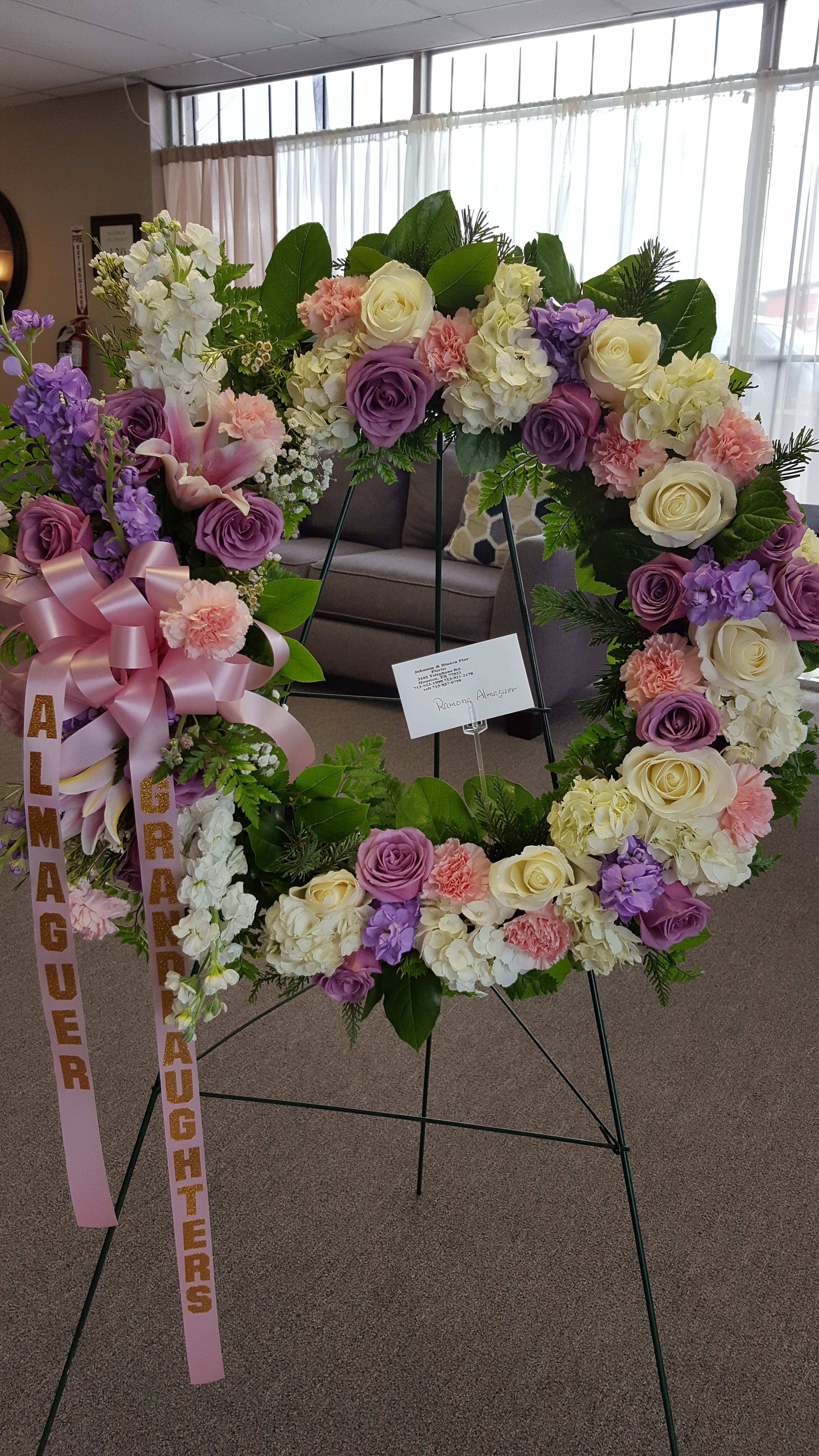 Large floral wreath with pink, purple, and white flowers on a stand