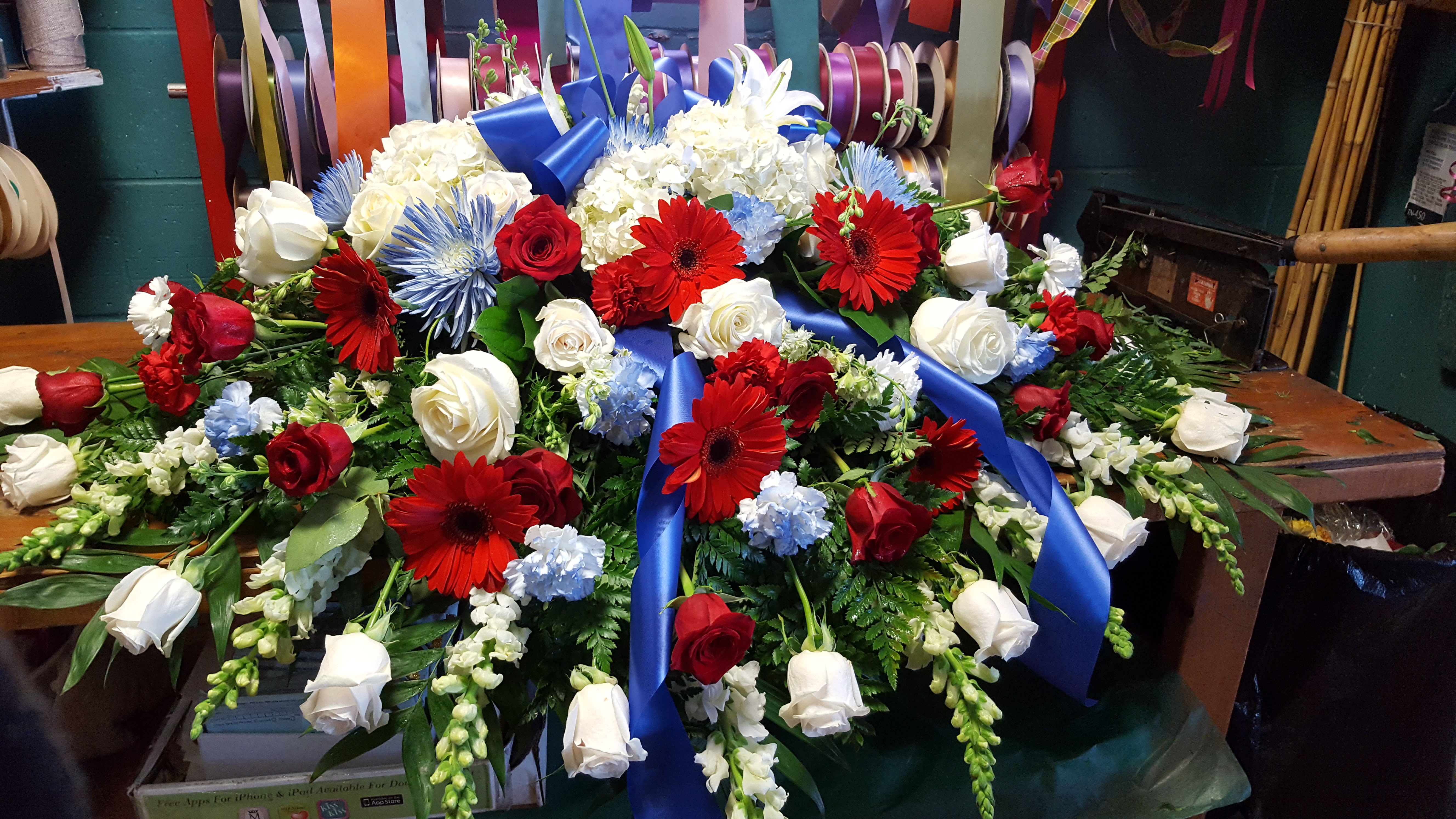 Large floral spray with red, white, and blue flowers and a blue ribbon
