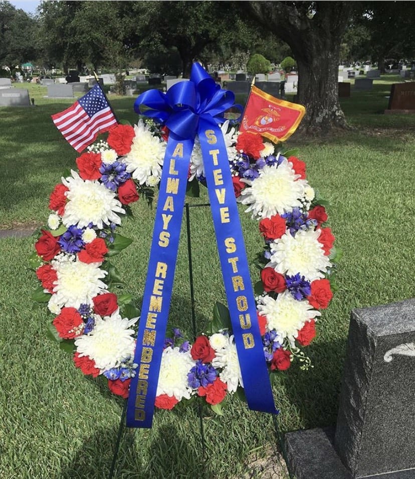 Patriotic funeral wreath with red, white, and blue flowers and ribbons