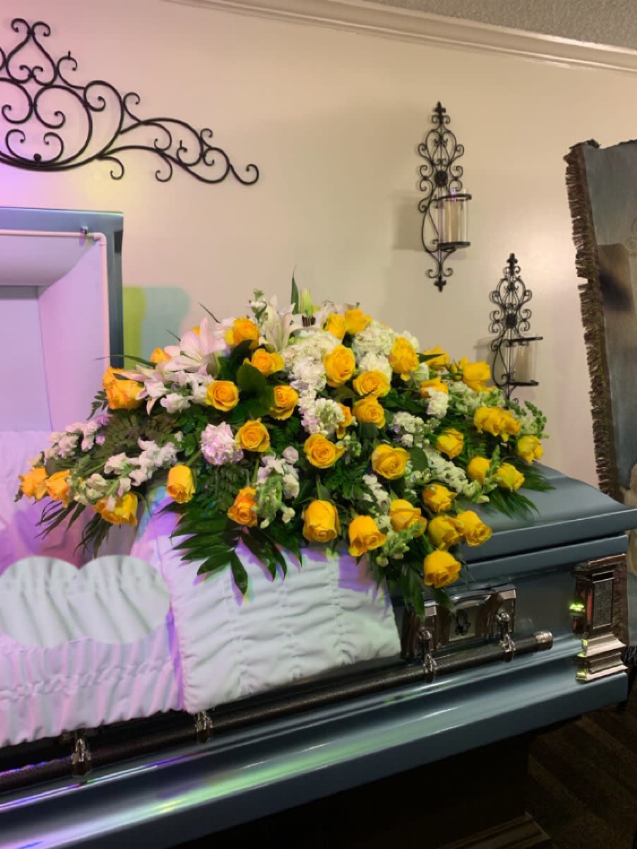 Large yellow and white floral spray on a casket