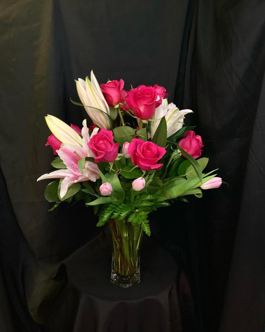 Pink roses and white lilies arranged in a clear glass vase