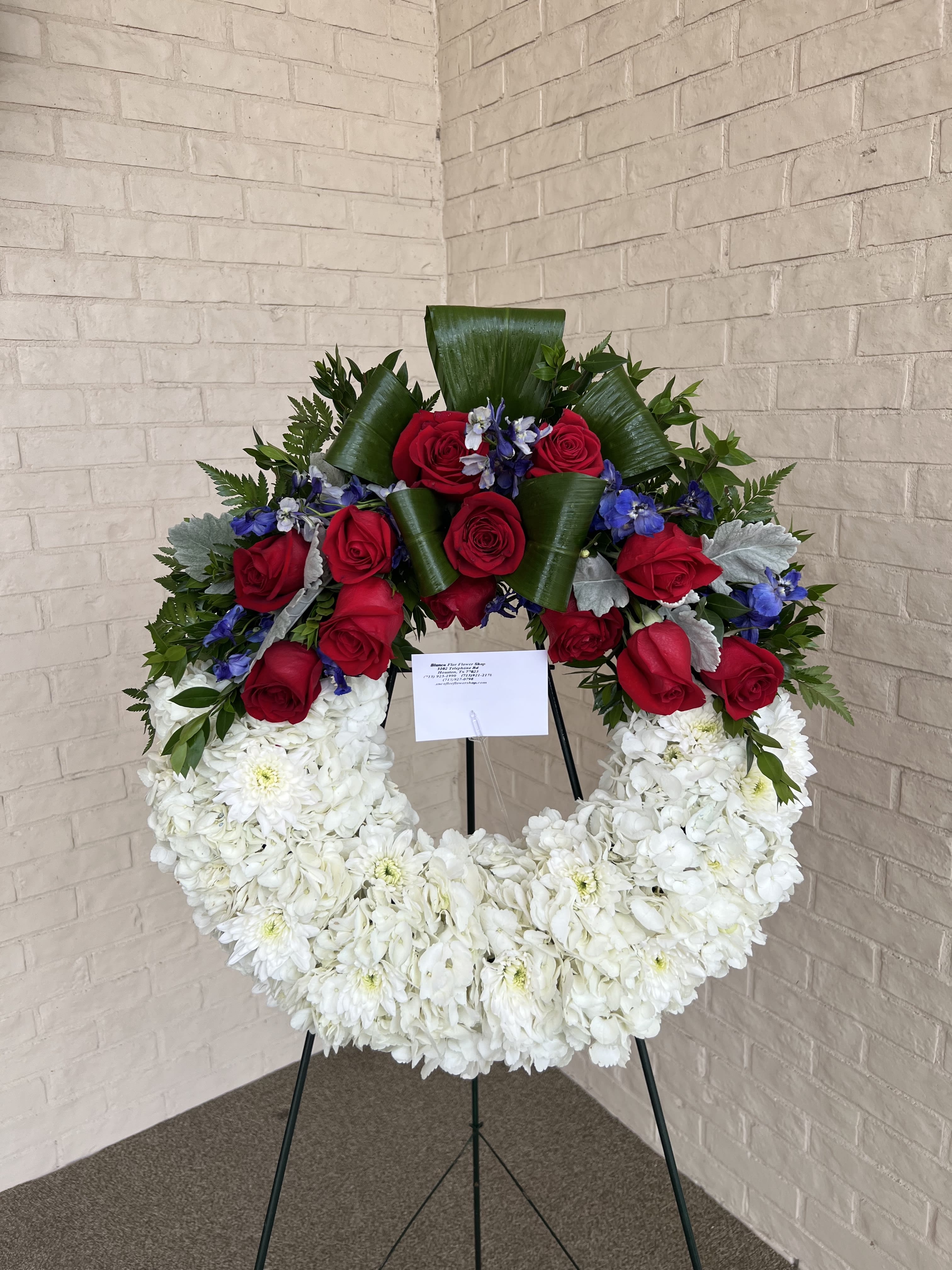 Circular floral wreath with red roses and white chrysanthemums on a stand
