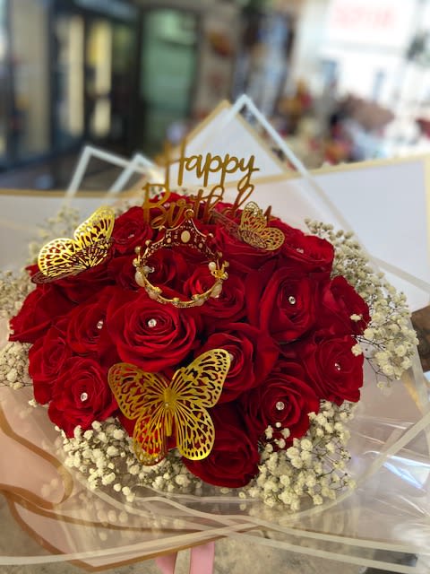Bouquet of red roses with gold butterfly decorations and a birthday topper